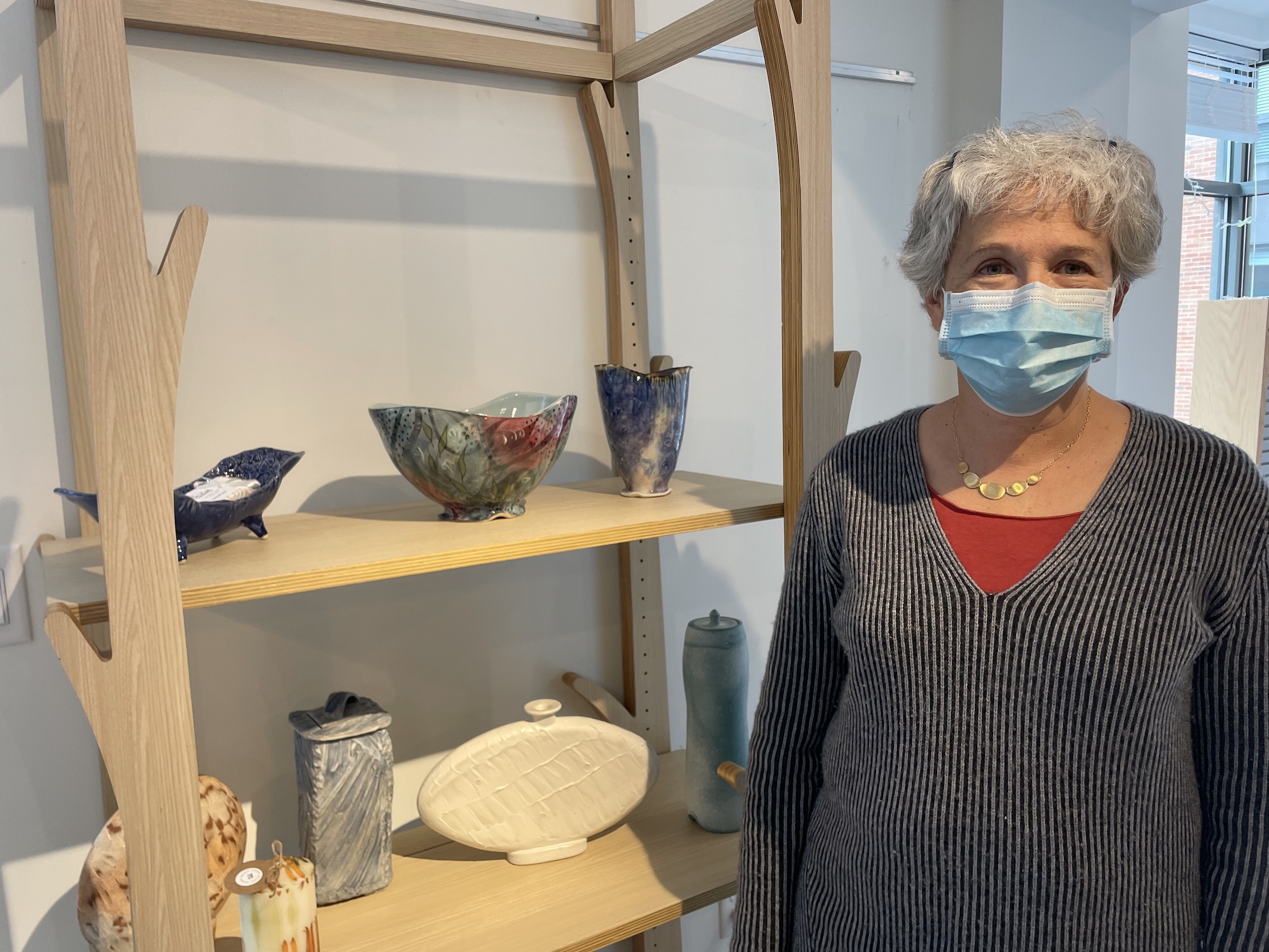 Ellen Weinberg shows her ceramics for sale on the second shelf of a display in the New Art Shop.