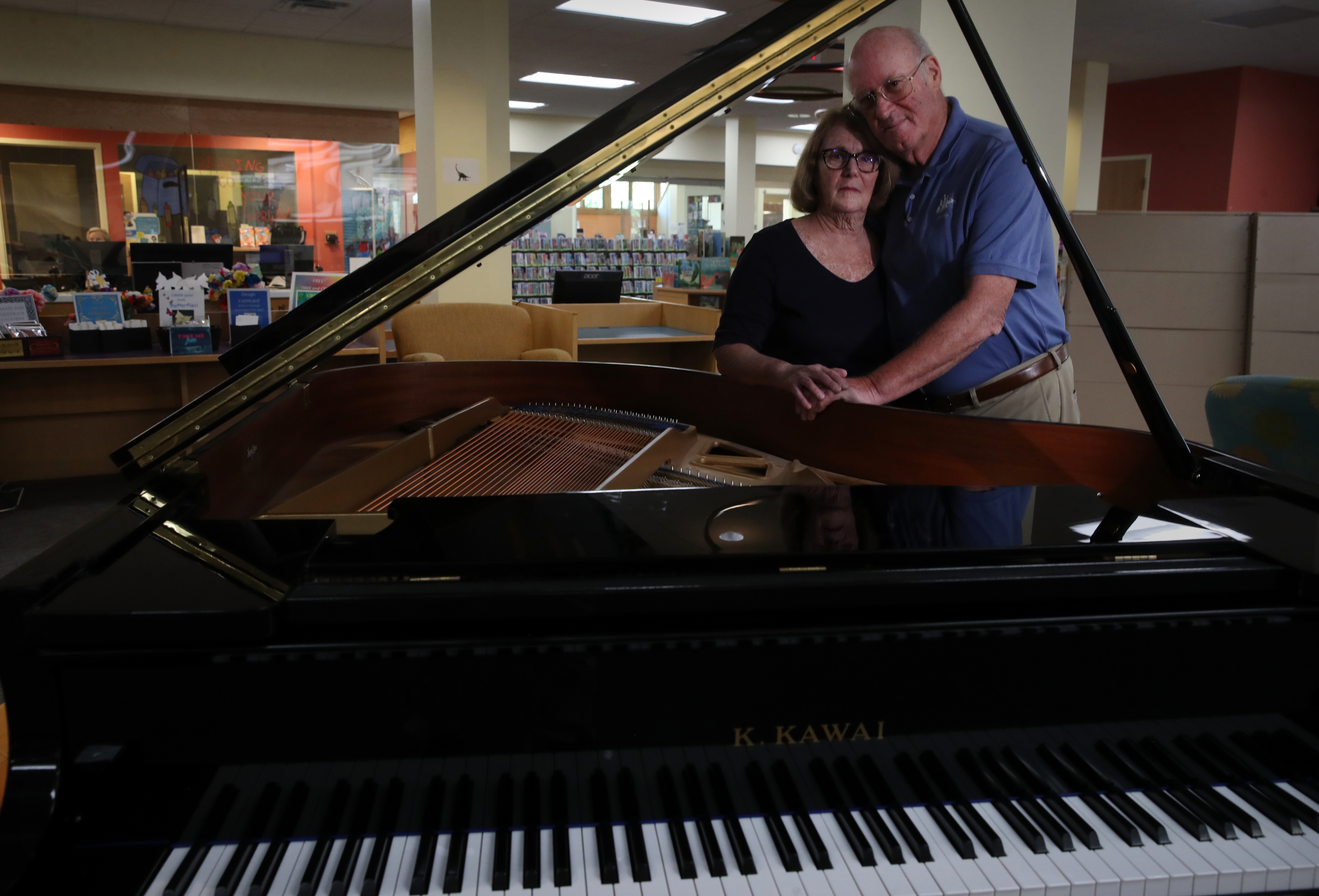 Dorine and Marty Toyen with their daughter's piano in the children’s room at the Avon Free Public Library in Avon, Conn.