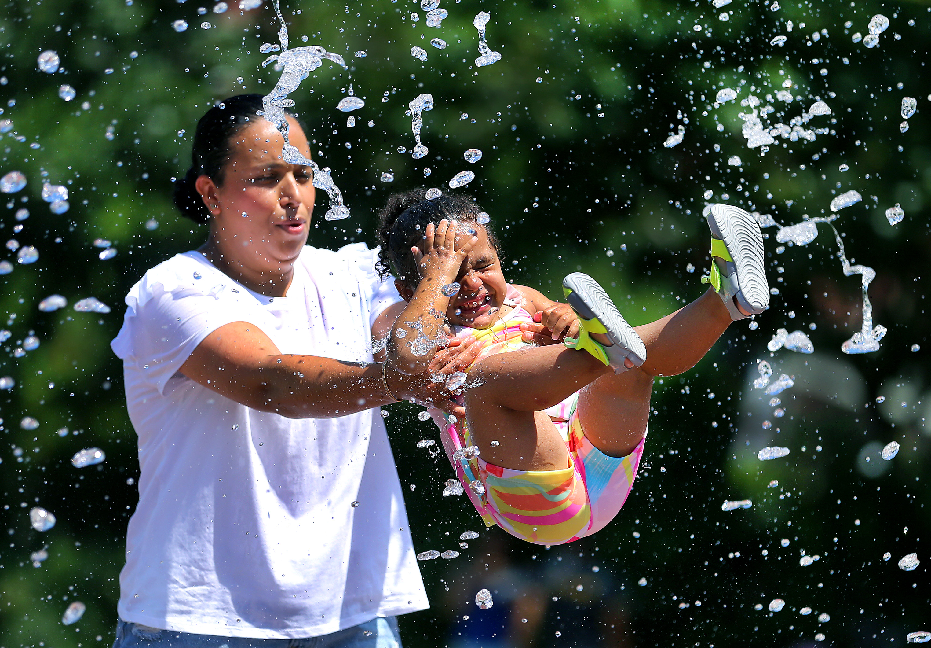 Gigi Ojly from Boston swings her daughter Amira 2 into the shooting waters of the Rings Fountain on the Greenway Saturday morning.