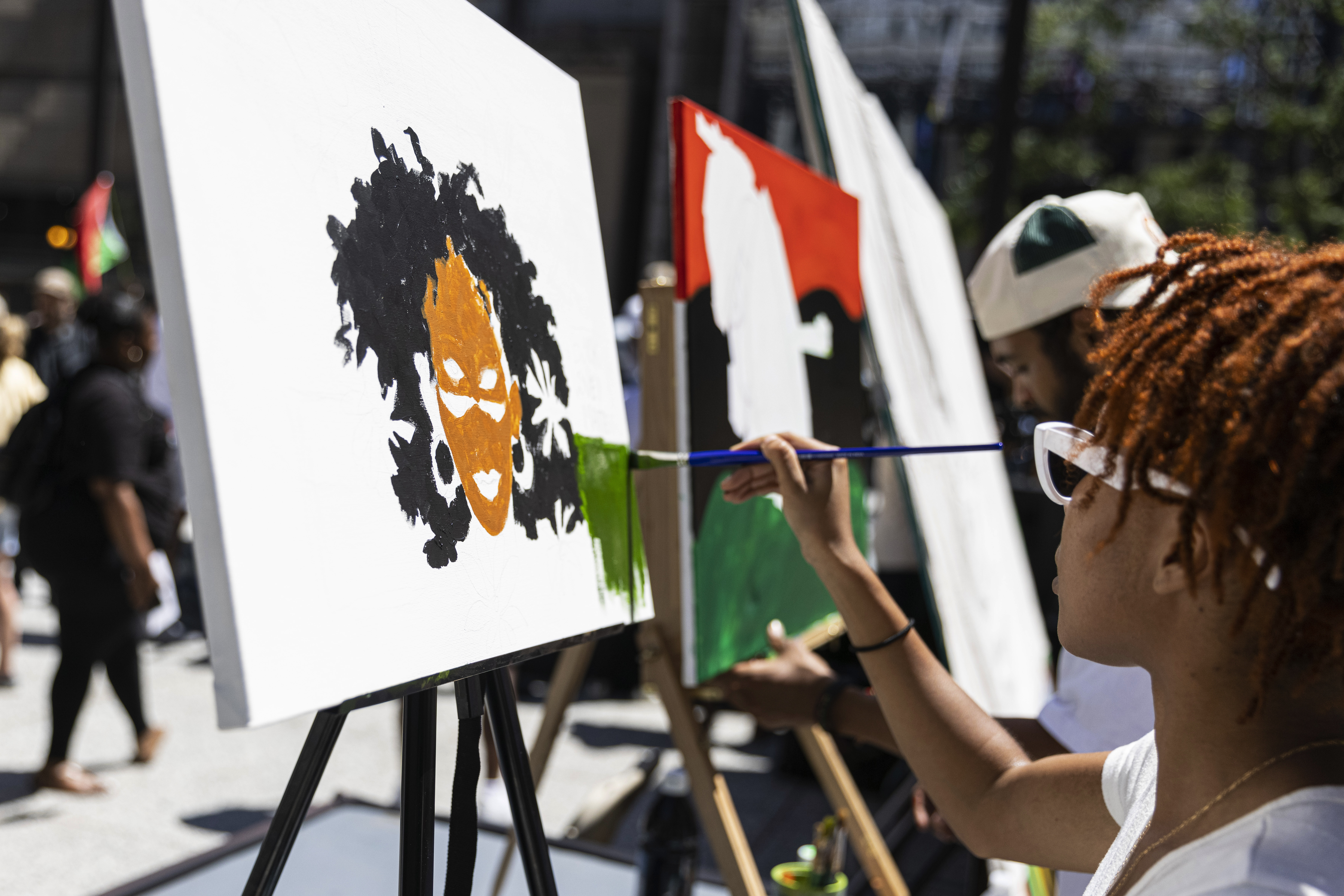 Artist Shiree Davis works on a painting as part of the March for Us rally by Voices for Youth in Chicago Education celebrating Juneteenth and celebrating the life of activist Caleb Reed at Daley Plaza in the Loop, Saturday, in Chicago.