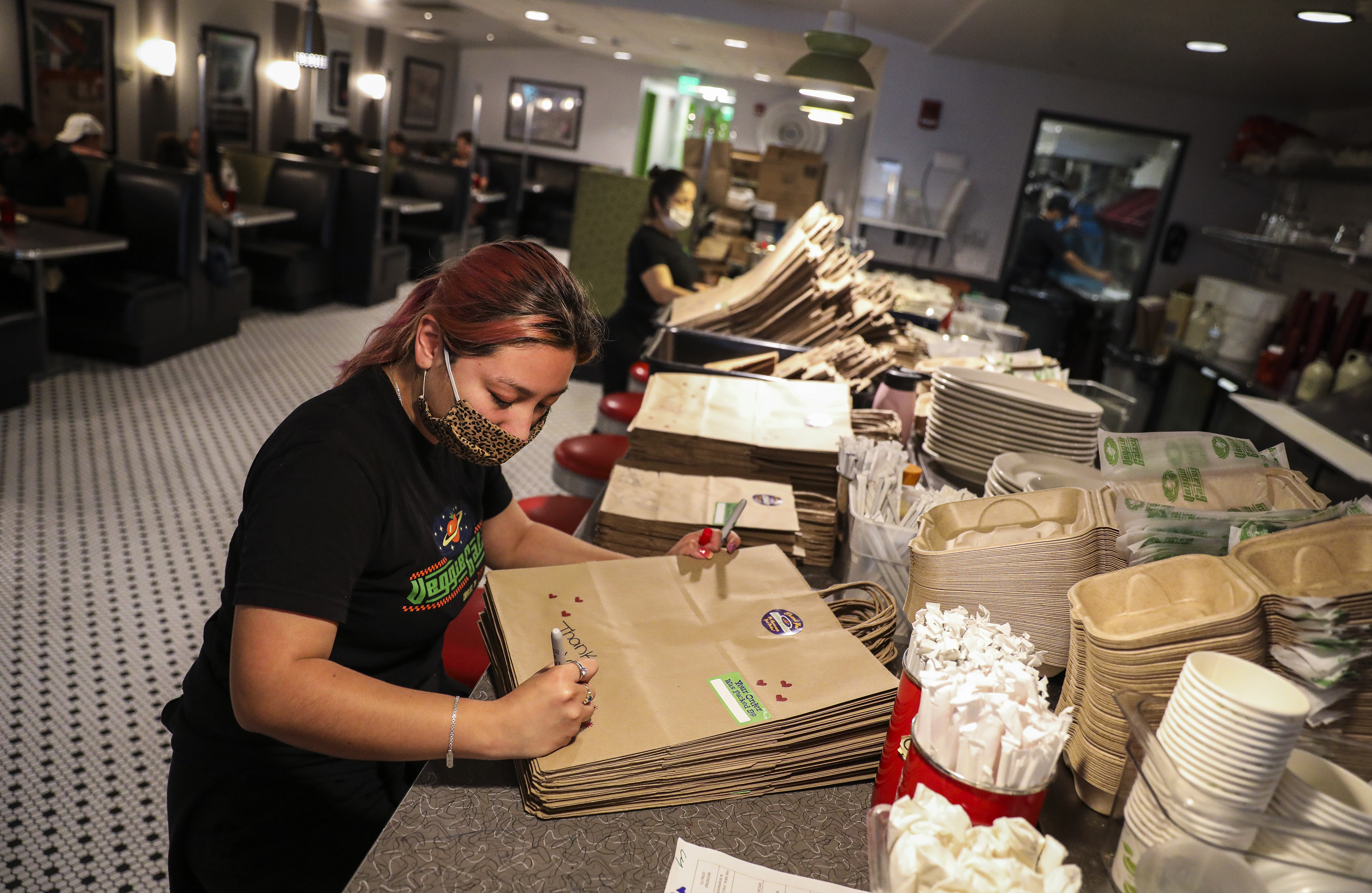 Rosa Martinez wrote personalized notes on take-away bags while working at Veggie Galaxy on Friday afternoon.  Owner Adam Penn isn't sure how the diner will keep up with online orders both indoors and outdoors. 