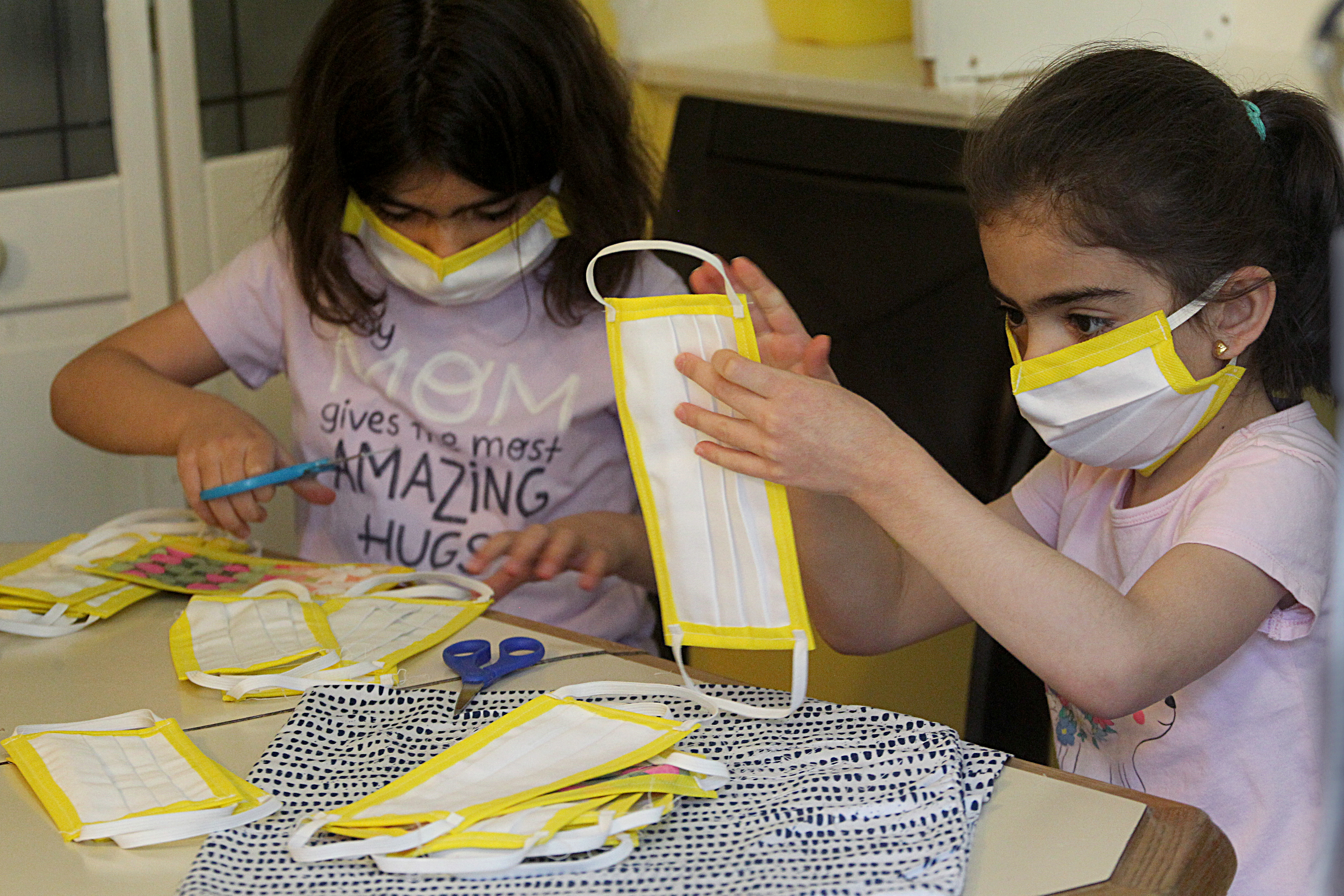 Fatimah and Ameeneh Hayani trimmed the extra threads on the masks their family made in the basement of their Shrewsbury home.