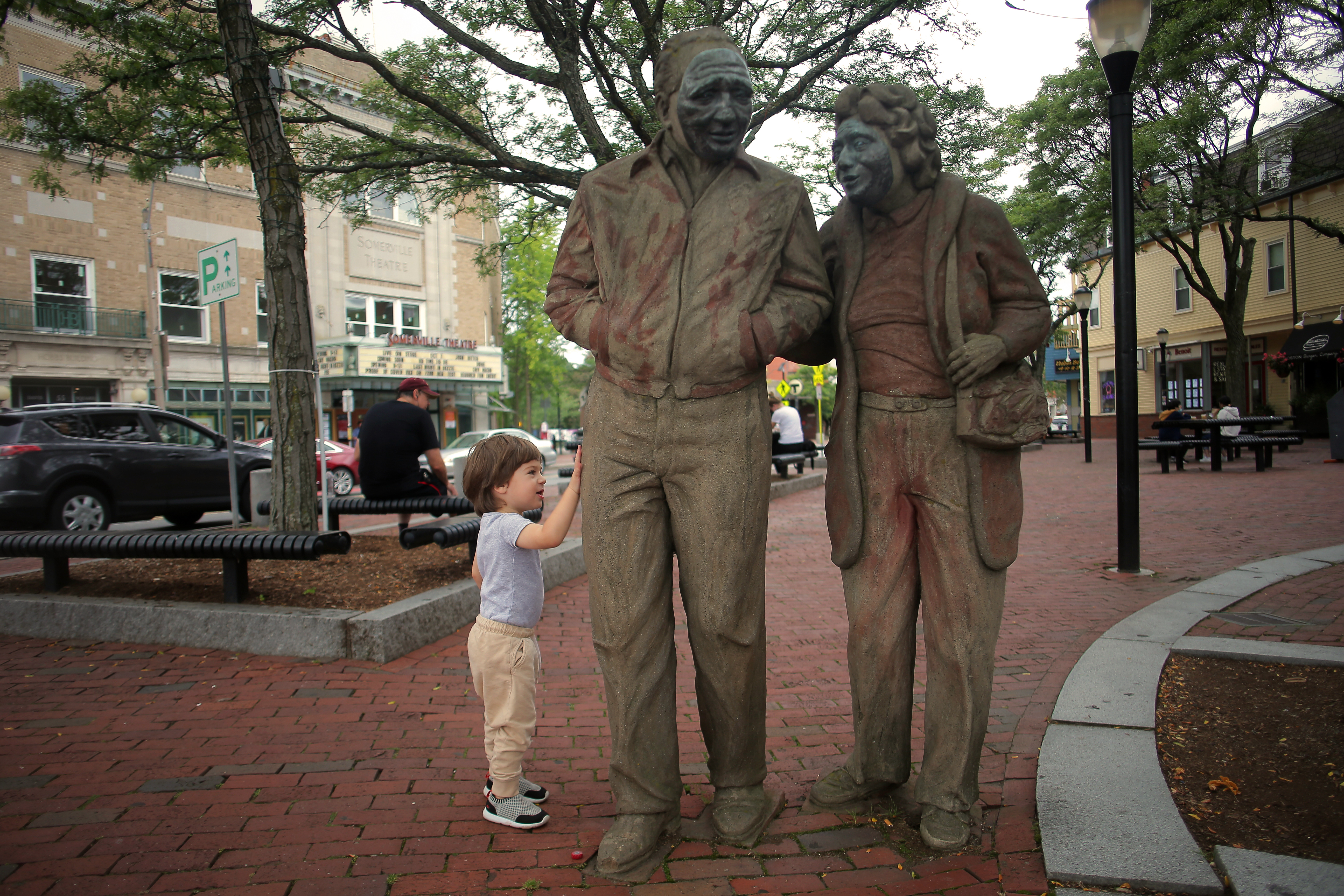 Nikki, 2, explores the sculpture of a couple walking arm in arm outside of the Davis station.