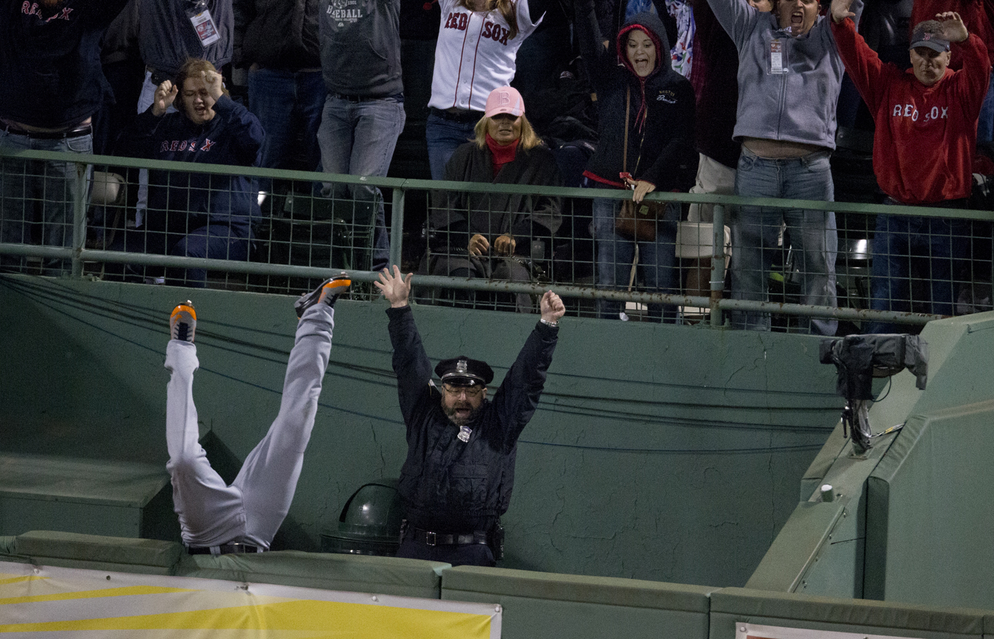 The Tigers' Torii Hunter flips over the bullpen wall trying to catch David Ortiz' grand slam during the 2013 AL Championship Series, as Boston Police officer Steve Horgan celebrates.