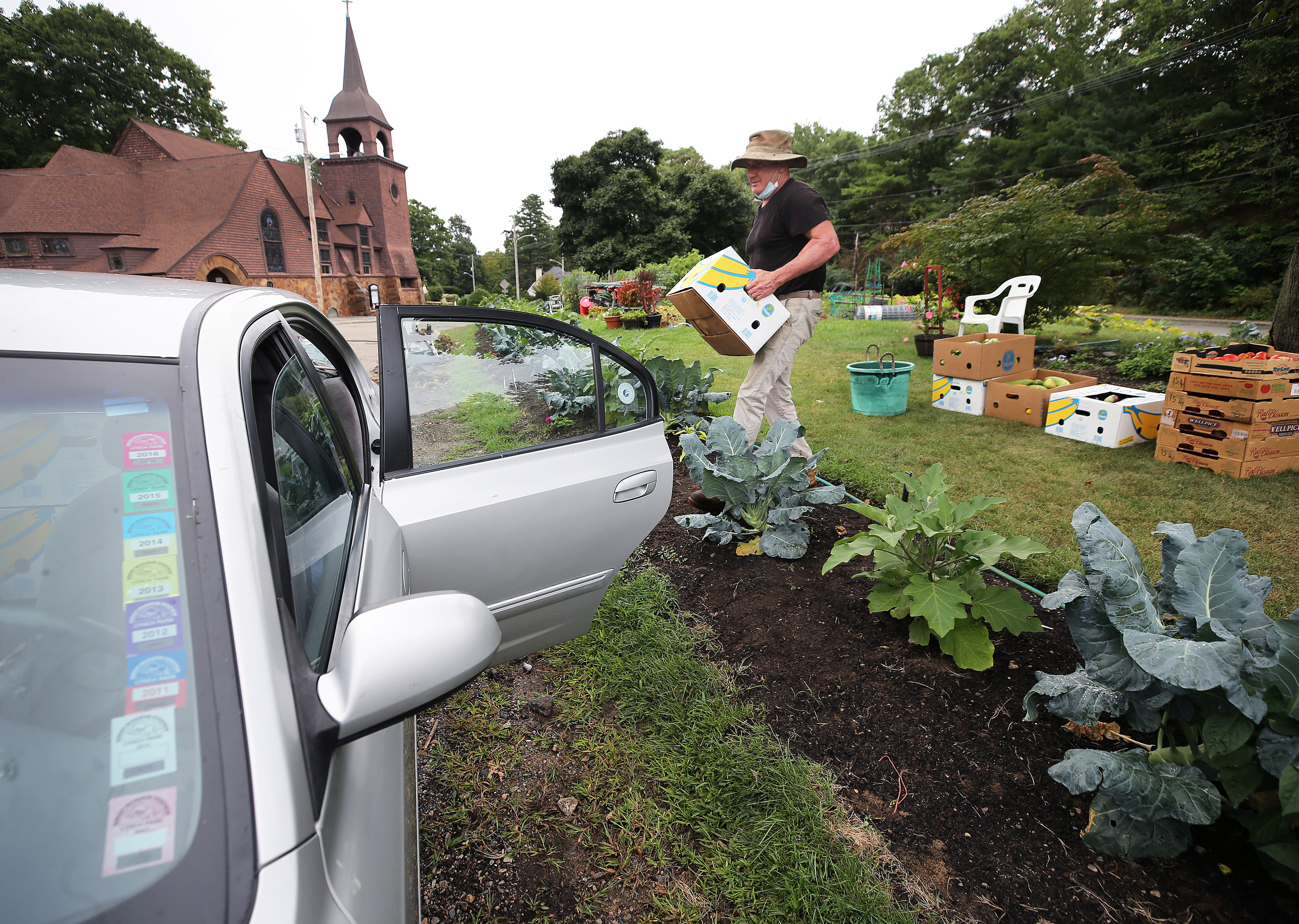 Fallon loads produce into his car at the traffic island in Beverly Farms. “Everyone should help those less fortunate than them,” he said.