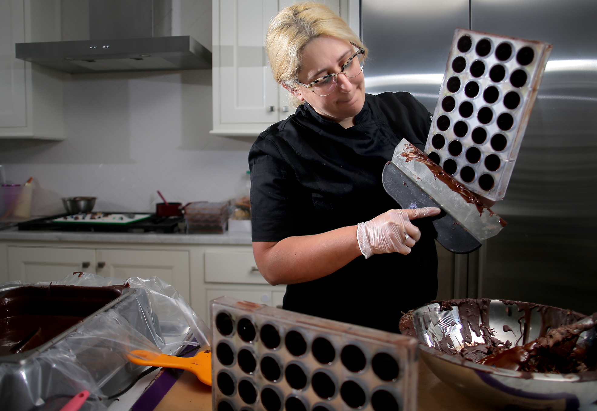 After filling molds with chocolate for the shells, Gal scrapes off the excess.