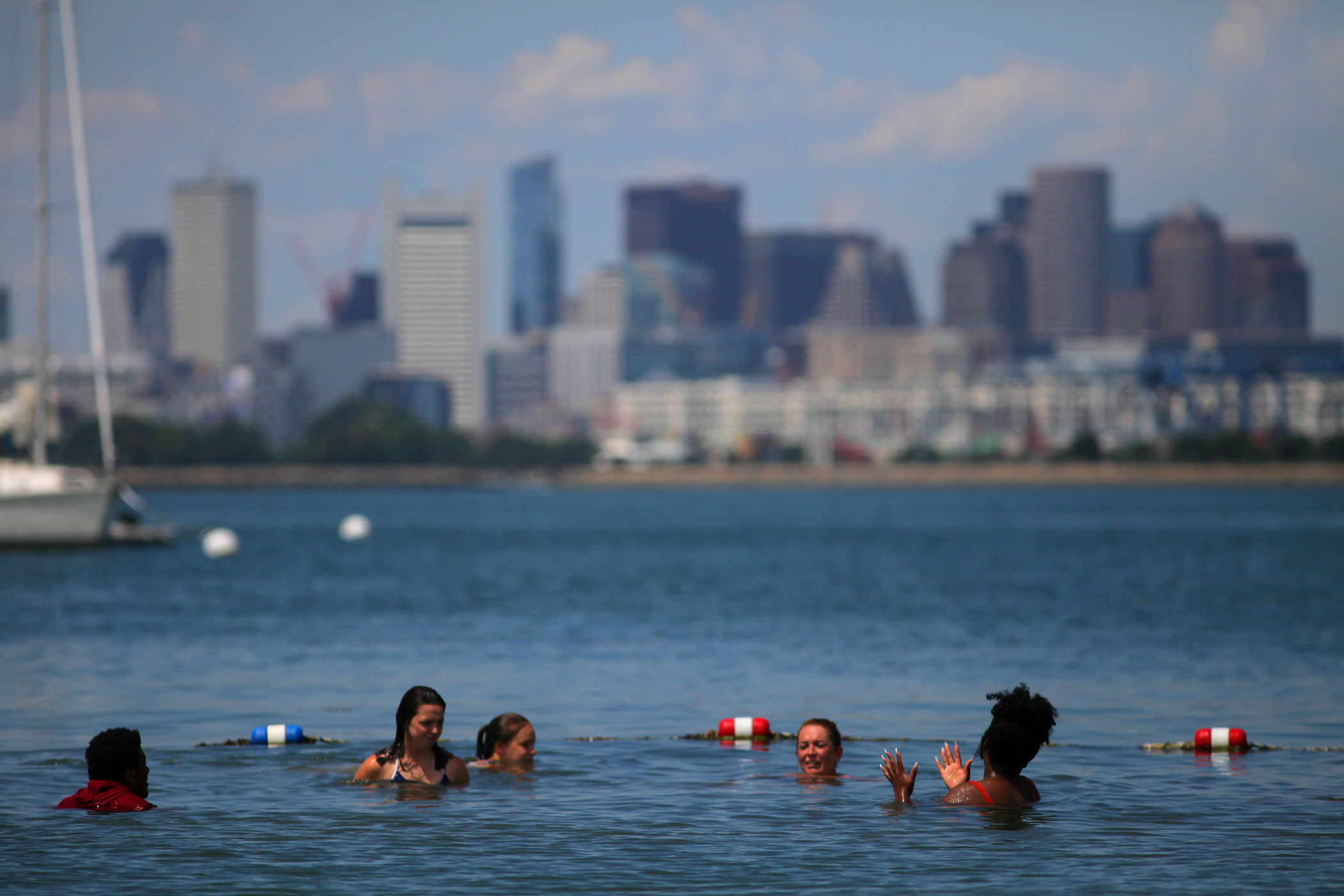 Boston's skyline provides a backdrop for swimmers enjoying the beach on Spectacle Island.