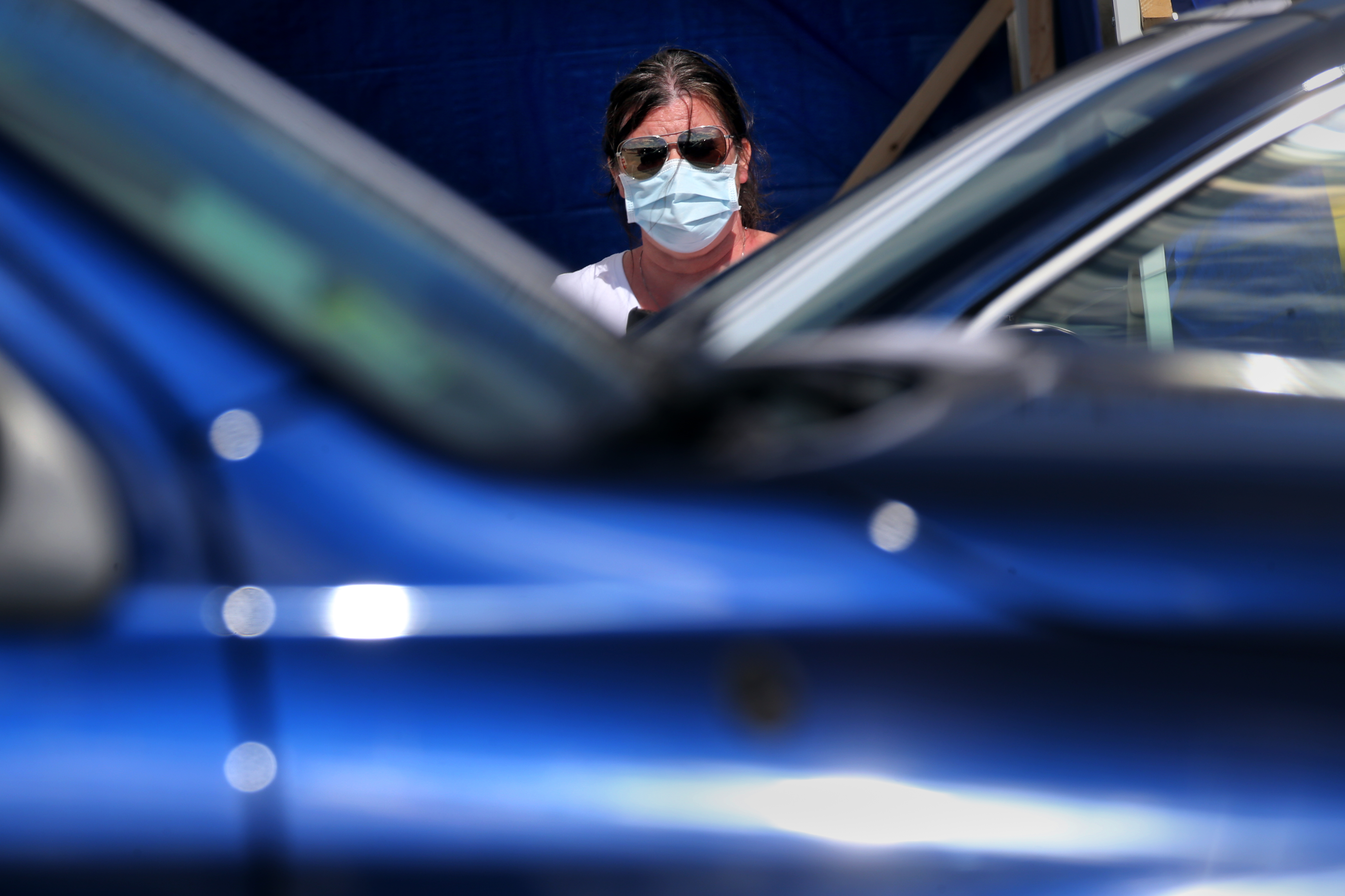 Lowell, MA - 4/7/2020: A woman directs vehicles as they arrive at a rapid COVID-19 testing site in Lowell, MA on April 07, 2020. (On Tuesday, April 7, CVS Health will launch the operation of a rapid COVID-19 testing site in Lowell, the first of its kind in the state. The drive-through site will offer no-cost testing to Massachusetts residents and will be capable of conducting and processing up to 1,000 tests per day, significantly bolstering the state's testing capacity. Recognizing the value of rapid testing to the state's efforts to combat and mitigate the spread of COVID-19, the City of Lowell actively partnered with the CVS Health and key state agencies, including the Executive Office of Health and Human Services (EOHSS) and the Massachusetts Emergency Management Agency (MEMA), to facilitate the expeditious launch of the testing operation. ) (Craig F. Walker/Globe Staff)