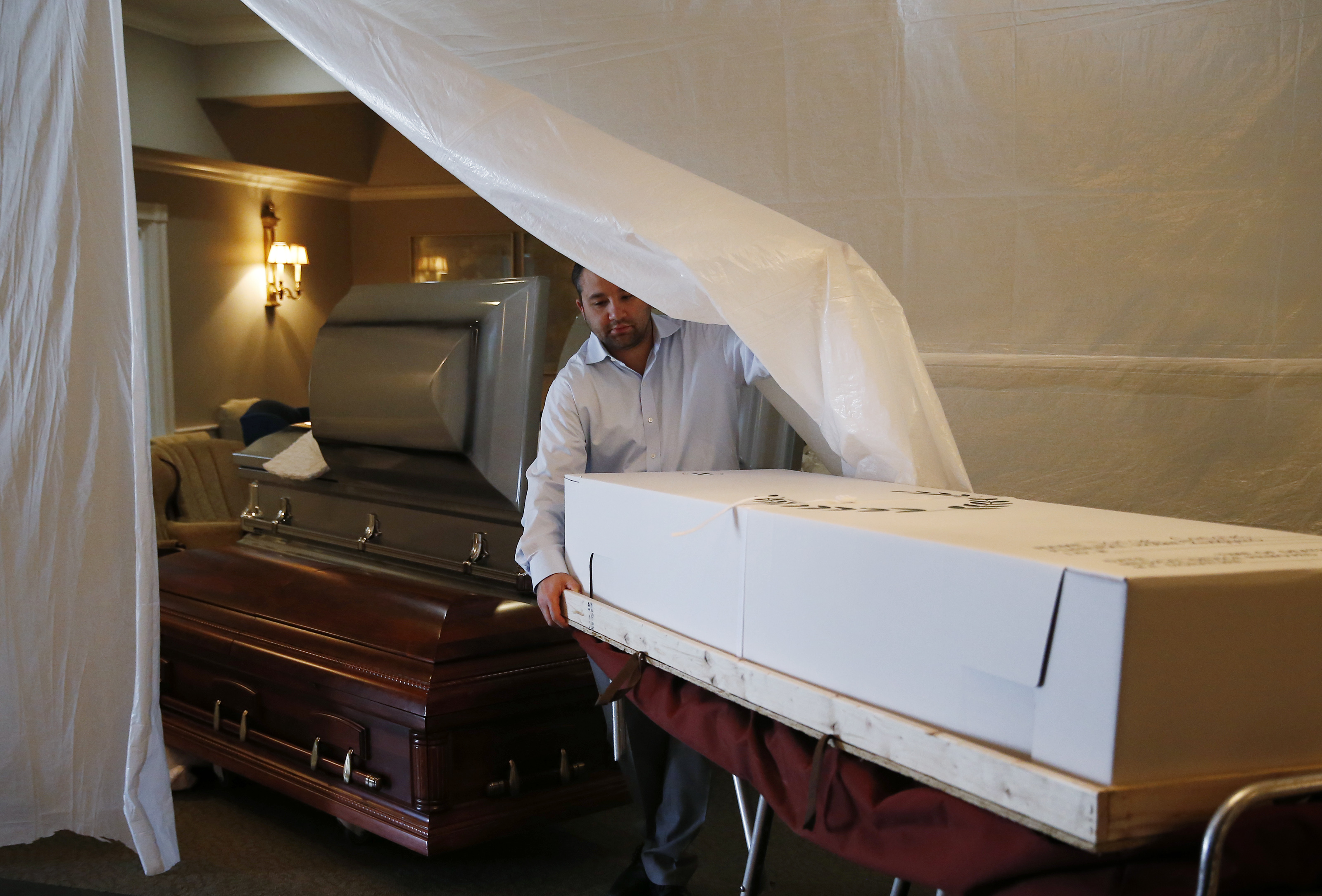 Funeral director Joe Ruggiero moved a body into a makeshift storage area.