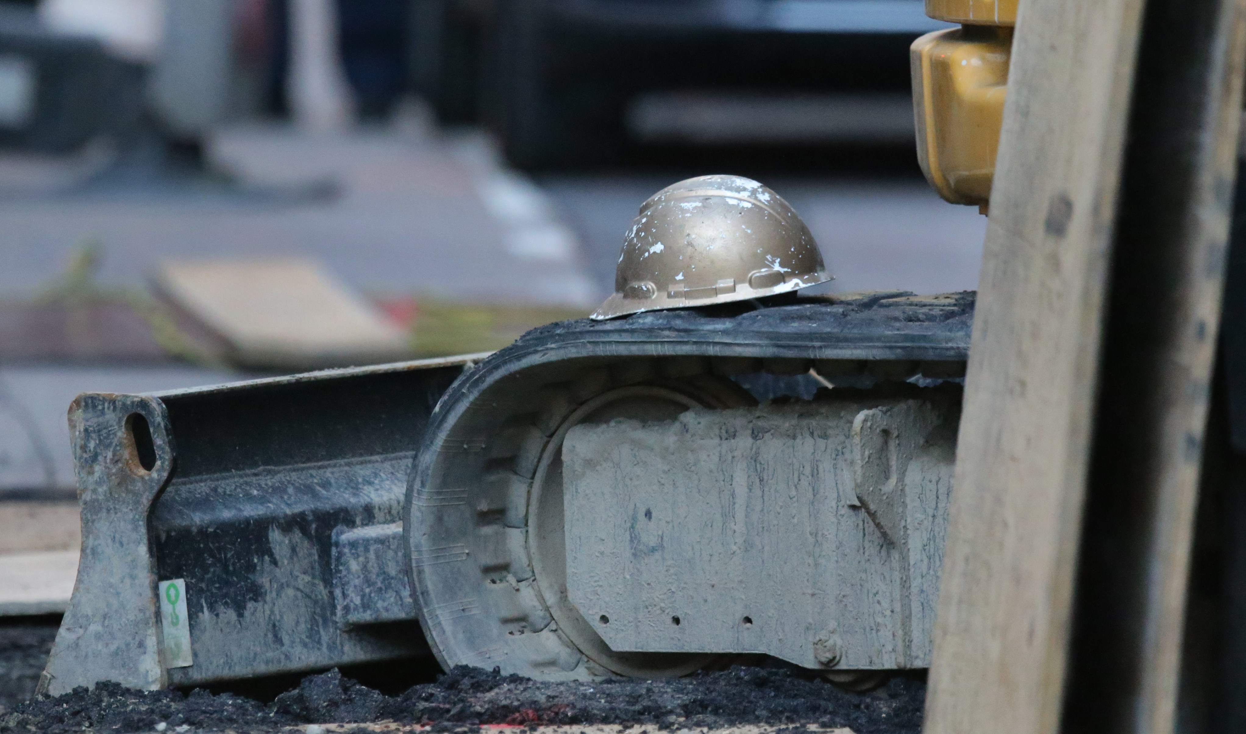 A construction hard hat at the accident scene on top of a construction vehicle by the hole where two construction workers died.
