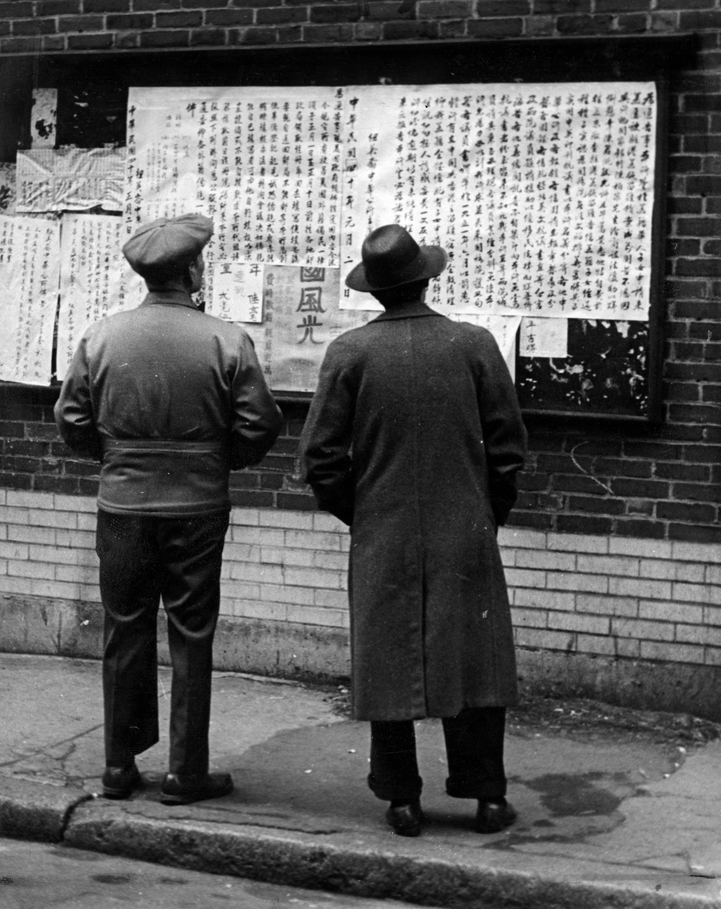 Men read posters informing residents of the "alien registration" regulations in Chinatown on Jan. 6, 1951.