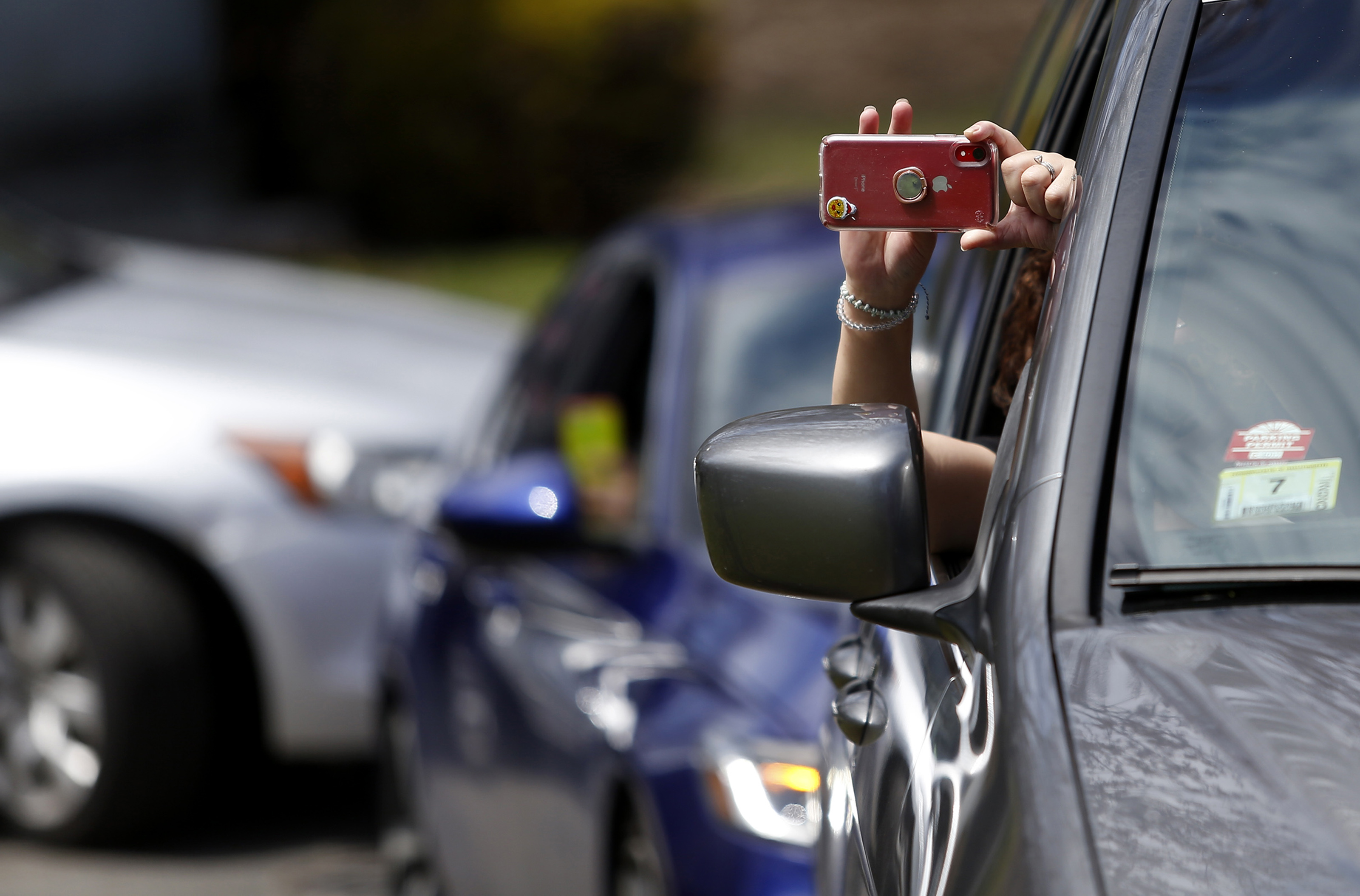 A mourner held a cellphone out to record as she attended Santos A. Rivas’s funeral from inside her car. Due to strict social distancing guidelines, only 10 people are allowed outside of their cars for graveside services at Woodlawn Cemetery in Everett.