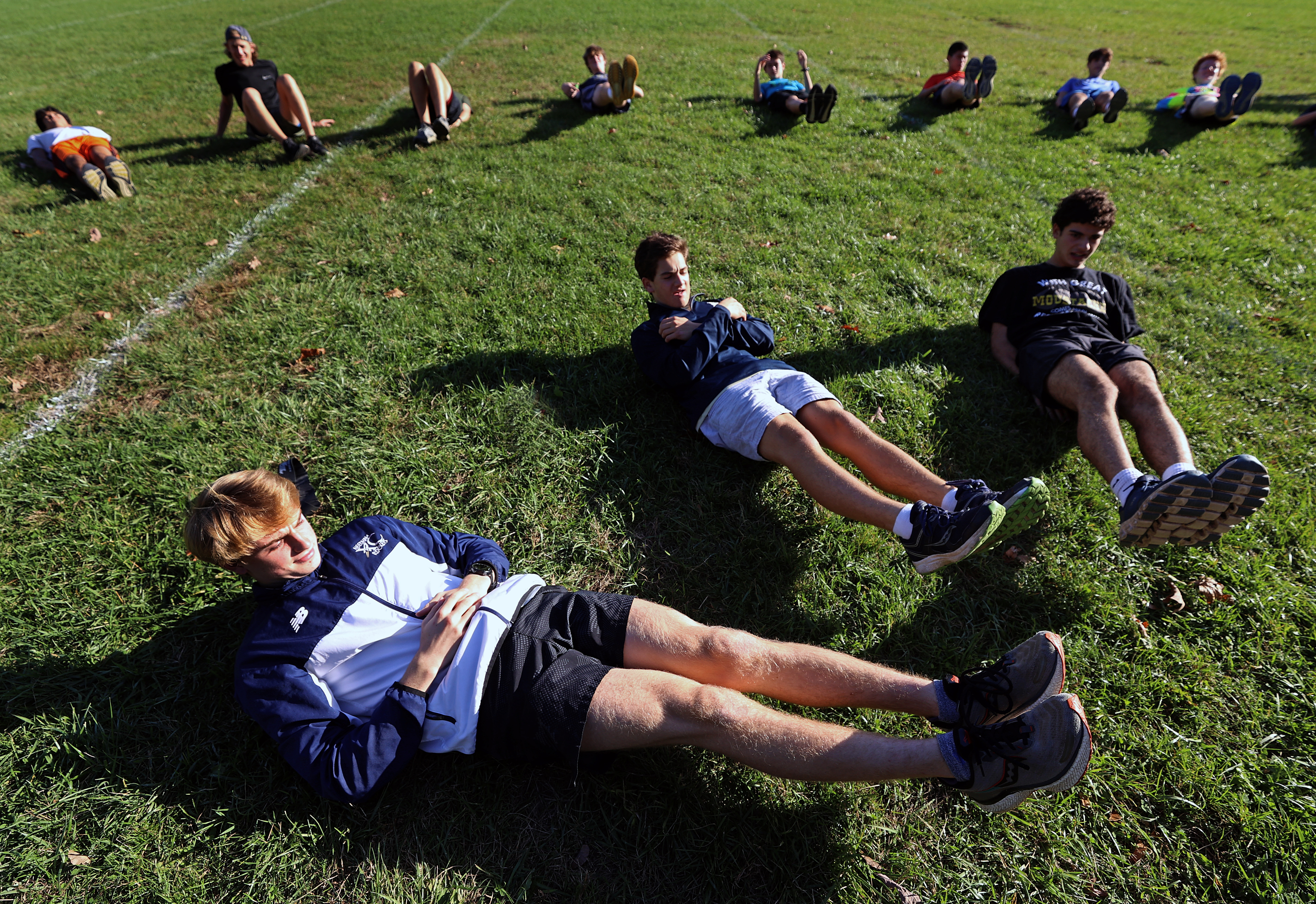 Kyler McNatt stretches along with his Needham teammates during a recent workout.