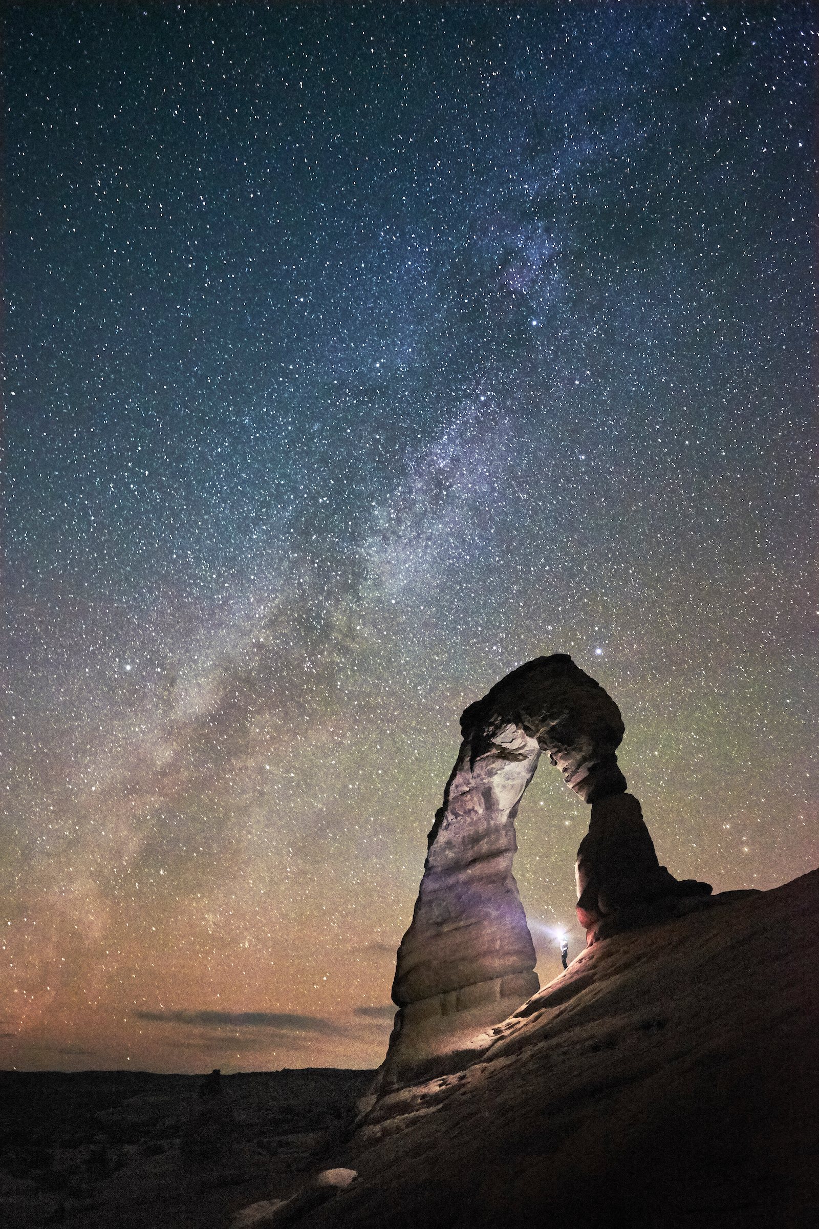 Delicate Arch in Arches National Park frames a starry sky.