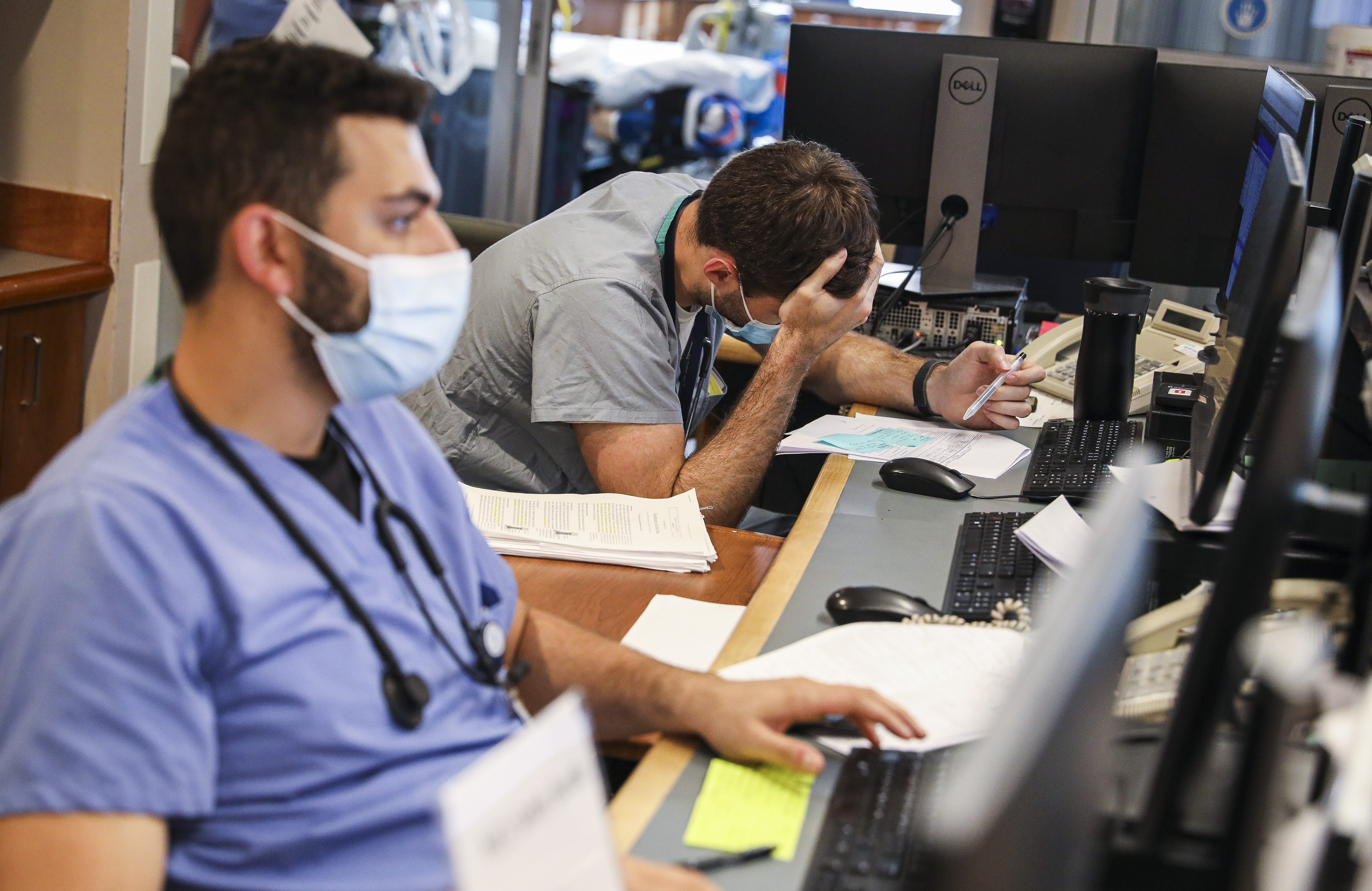 Doctors Basel Humos (left) and Benjamin Schwartz are working behind the desk in the medical intensive care unit at Tufts Medical Center on Thursday.