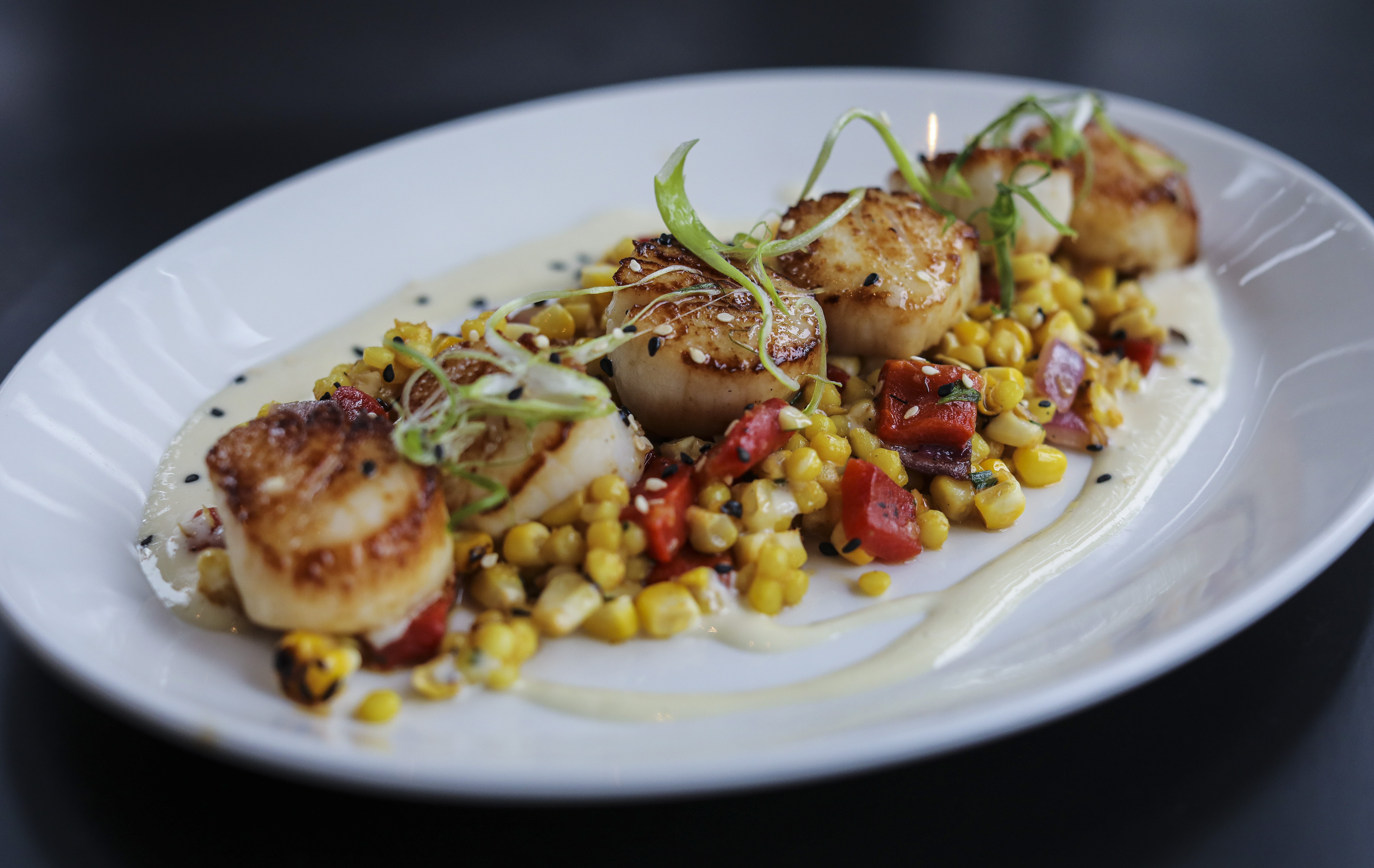 Seared scallops with grilled corn, white soy vinaigrette, and roasted pepper. 