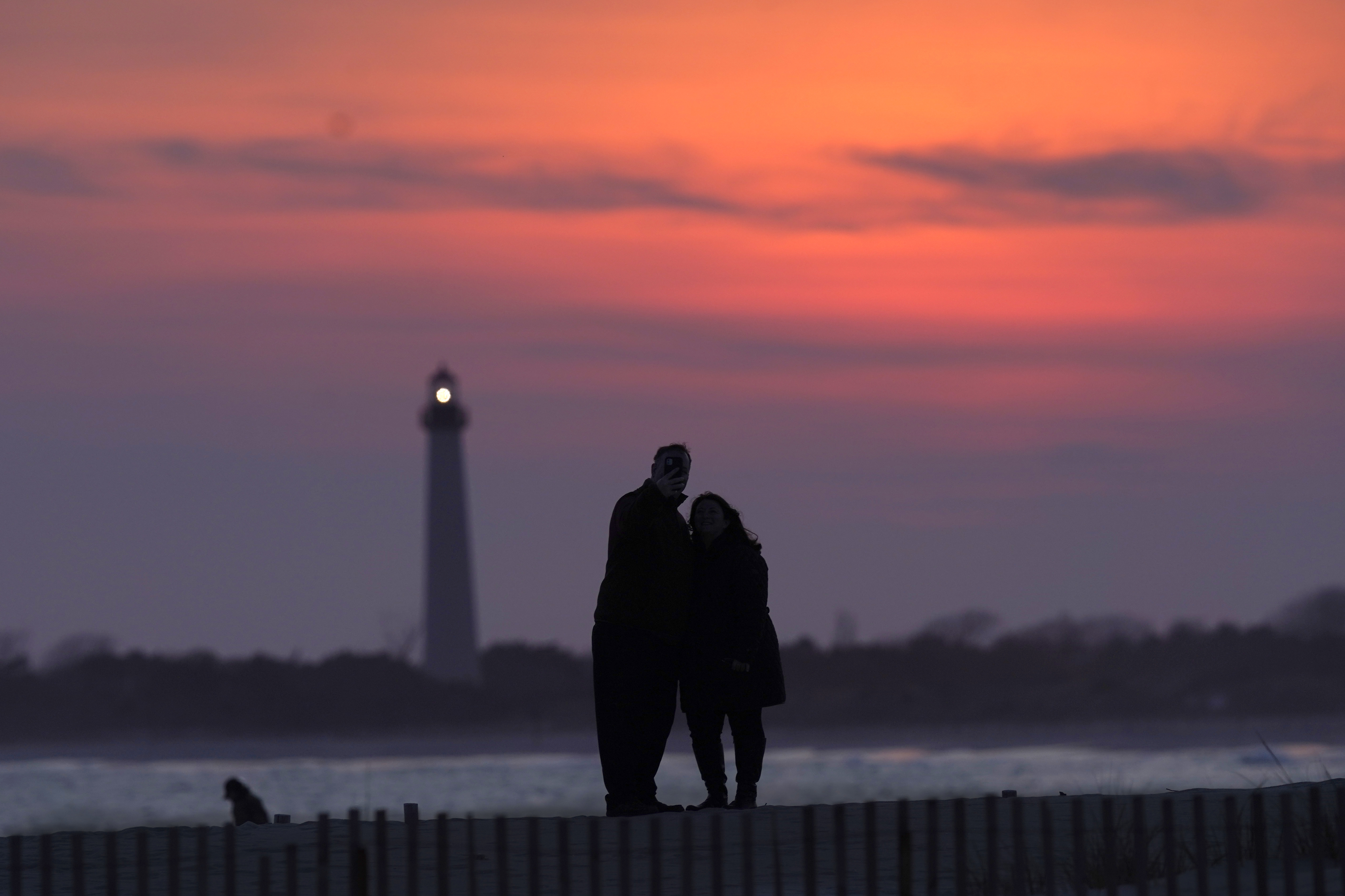 Visitors to Cape May, N.J., watch the sunset behind the Cape May Lighthouse, April 8, 2021.