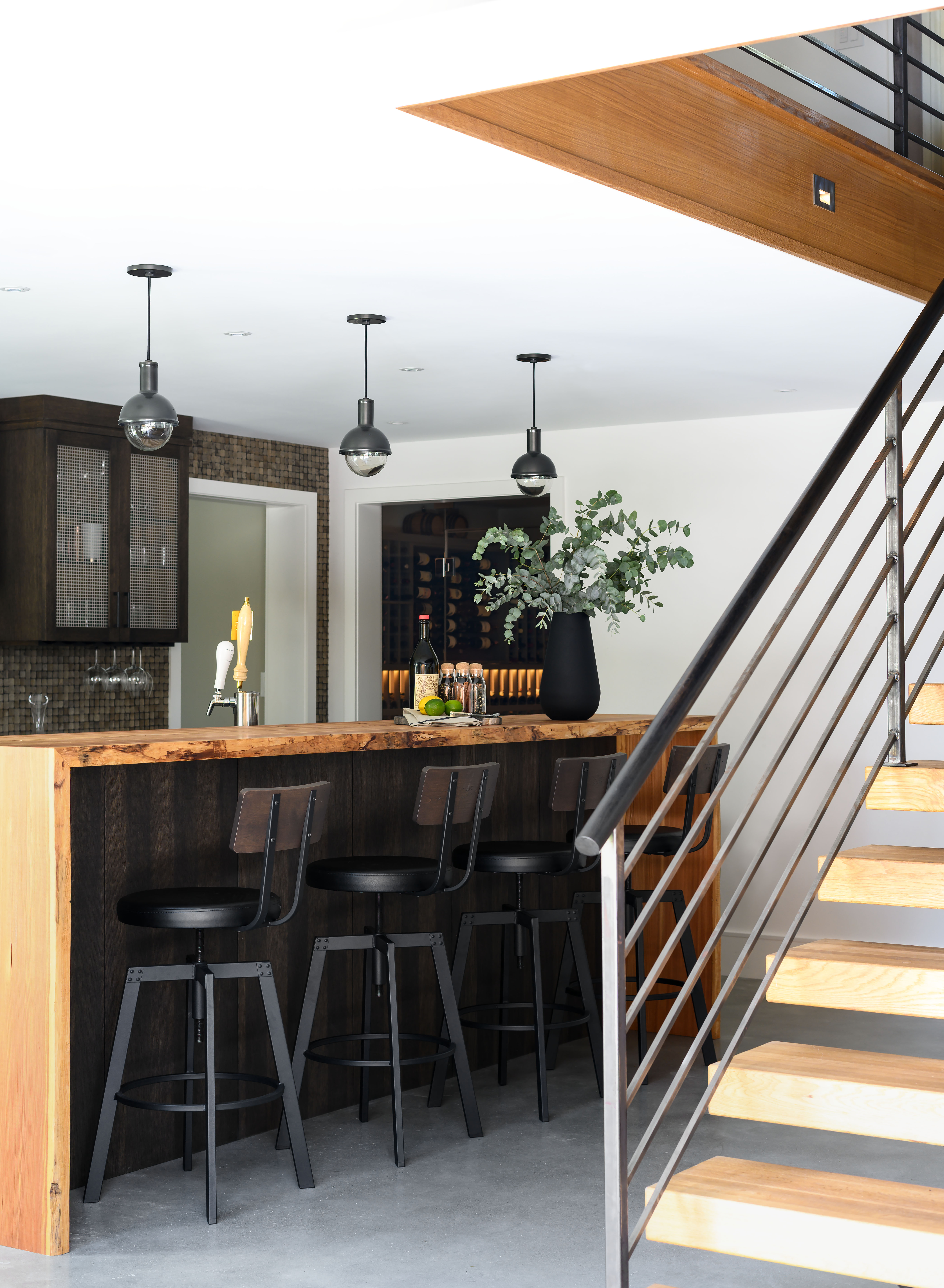 Newburyport craftsman Brian Days of Red Birch Designs built the cabinetry for the bar on the lower level. It has a live-edge larch wood top and a backsplash made from carved coconut shell tiles by EccoTessa.