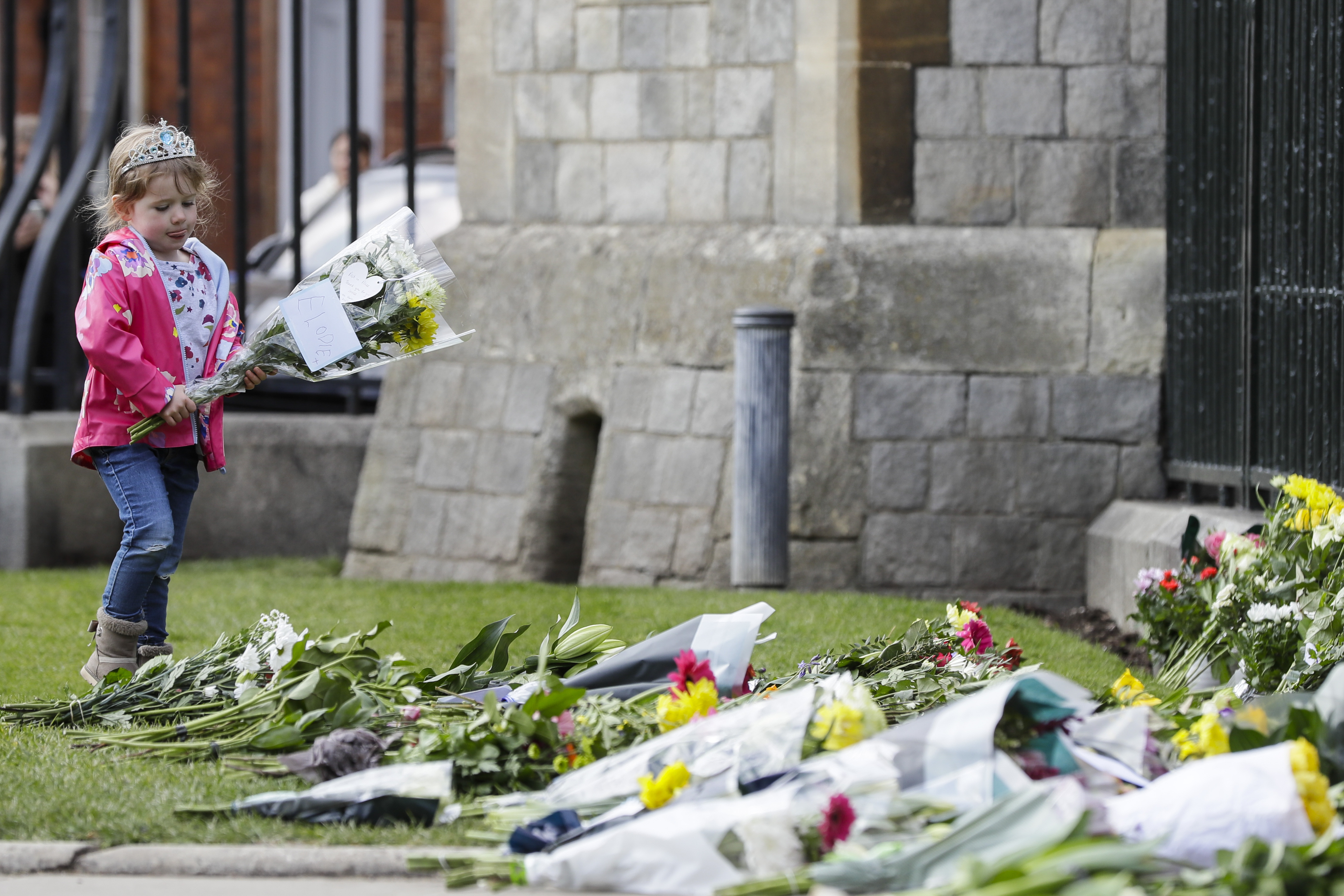 A child brought flowers outside the Cambridge gate of Windsor Castle in Windsor, England after the announcement regarding the death of Britain's Prince Philip.
