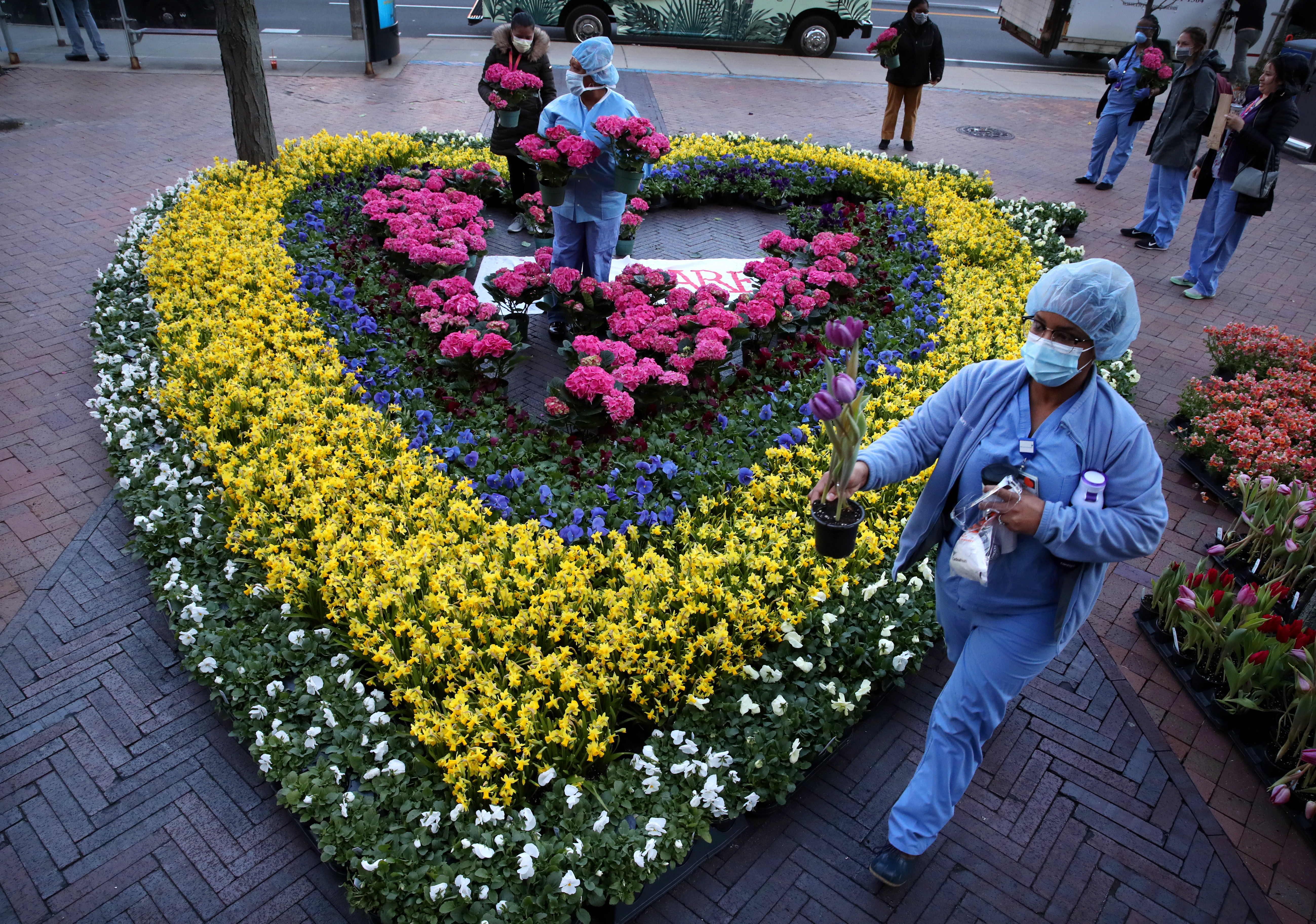 Boston,MA - 4/10/2020: Staff members choose flowers outside Beth Israel Deaconess Medical Center in Boston, MA on April 10, 2020.  About 1,000 spring flowers, some of which were going to line the route of the 2020 Boston Marathon, were arranged in a heart outside Beth Israel Deaconess Medical Center and given to health care workers Friday morning as they conclude long shifts at the hospital. Hydrangeas, tulips, pansies, and daffodils were placed outside Beth Israel by workers from Cityscapes, the Boston-based floral company behind the gesture. Cityscapes owner Jan Goodman came up with the idea to support health care workers in the way she knows best — with flowers. (Craig F. Walker/Globe Staff) 