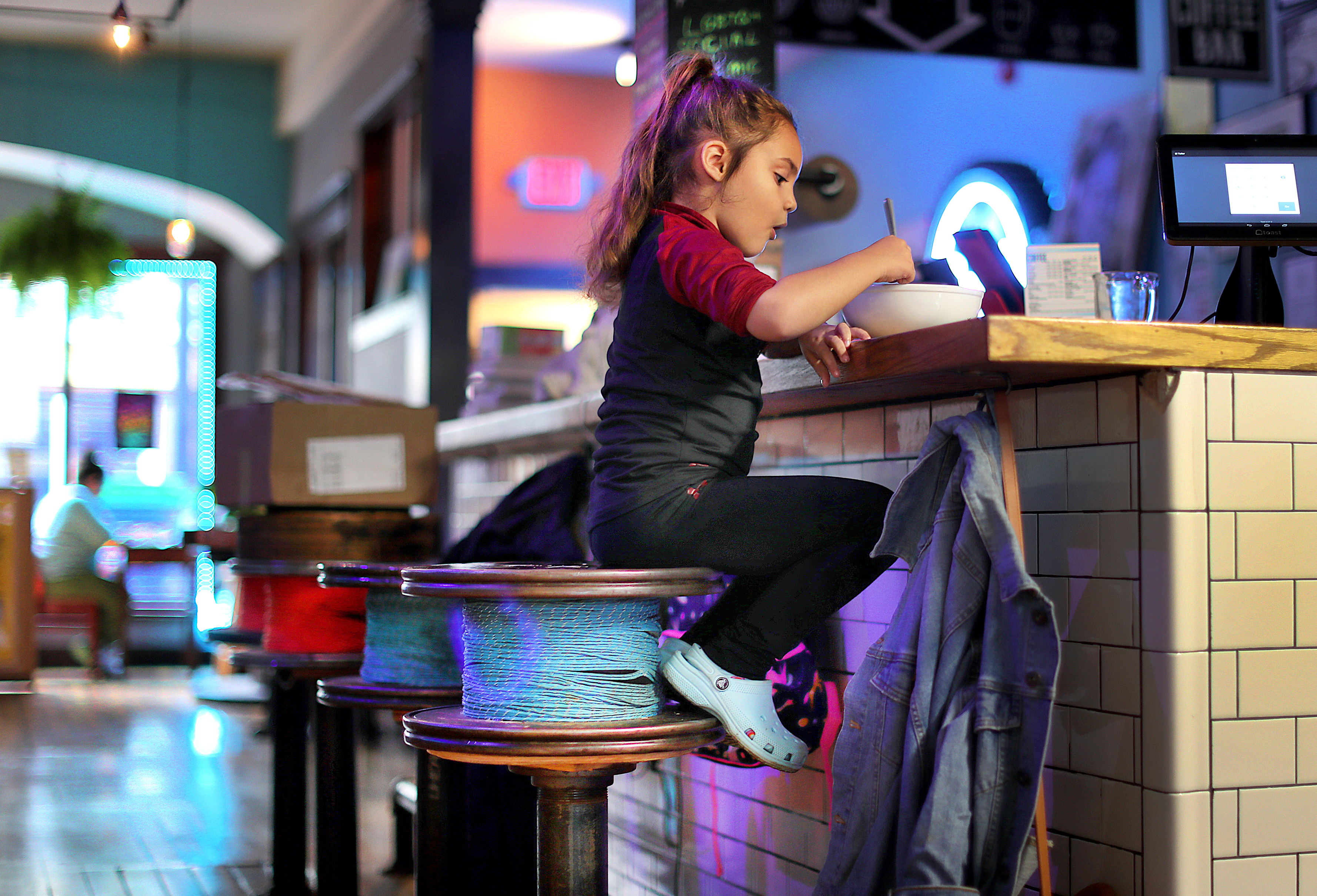 Stella Rose Torres, 4, had a salad at the counter of El Taller, an eatery popular with the artist community in Lawrence where her mother works. She sat on a repurposed fabric spool saved from a Lawrence textile mill.