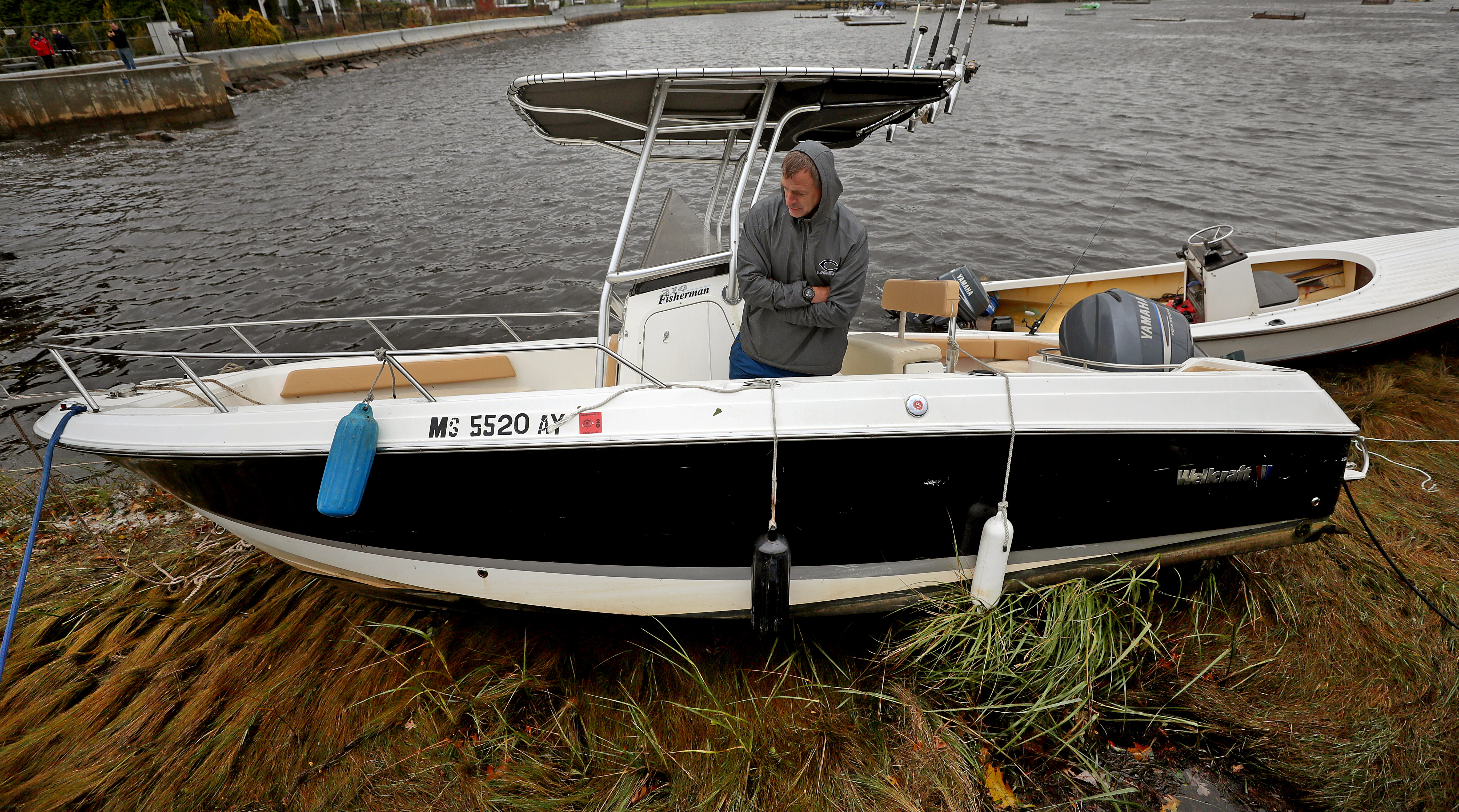 Paul Appleton from Cohasset stood on his boat that washed up on the marsh during the storm in Cohasset Harbor and waited for high tide.