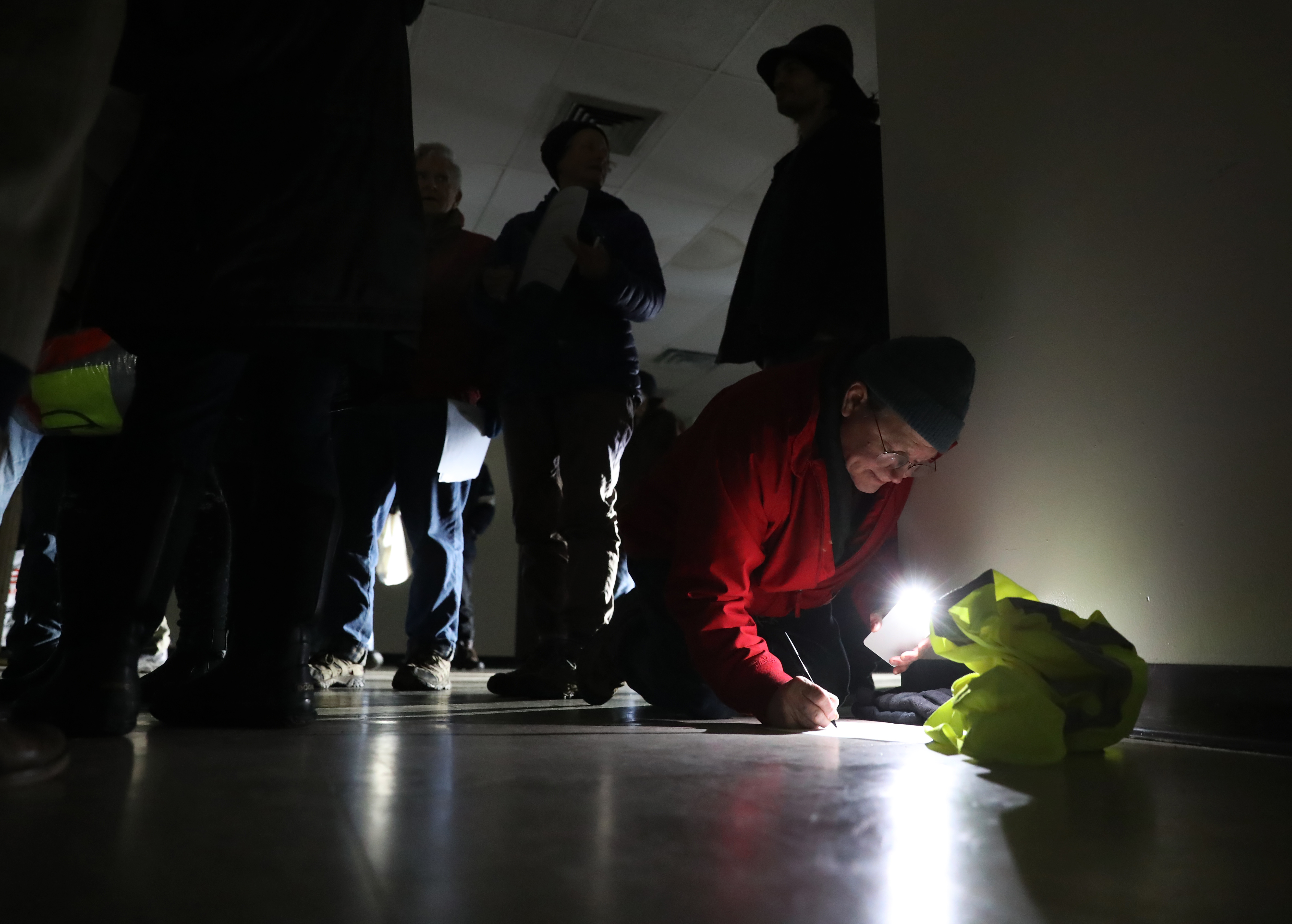 David Klafter of Brookline used the light from his cell phone to sign some paperwork on the floor in a building used for protesters who gathered before demonstrating against the controversial Weymouth compressor project on January 15.