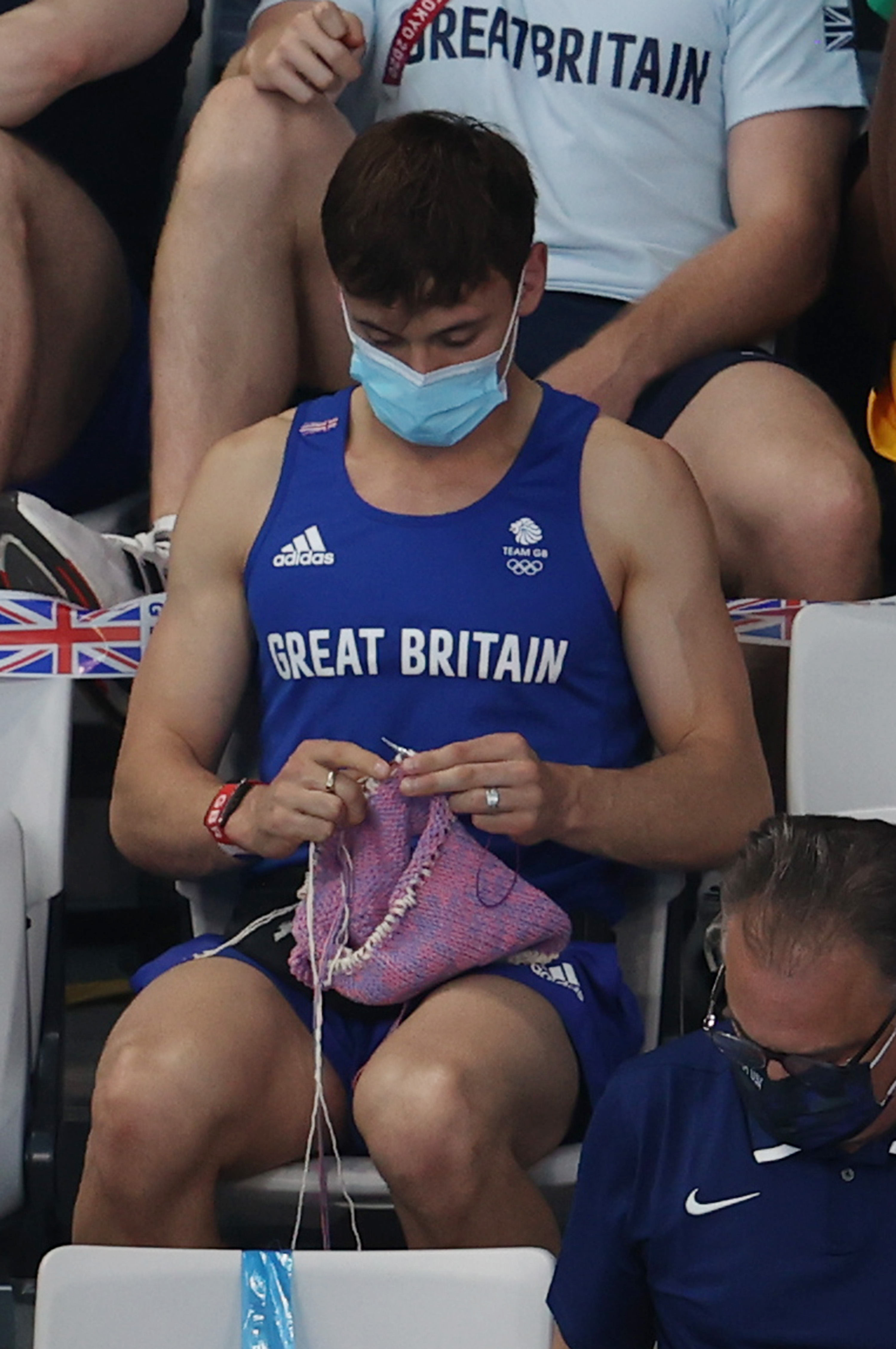 Tom Daley of Great Britain knits as he watches the women's 3-meter springboard final at the Olympic Games.