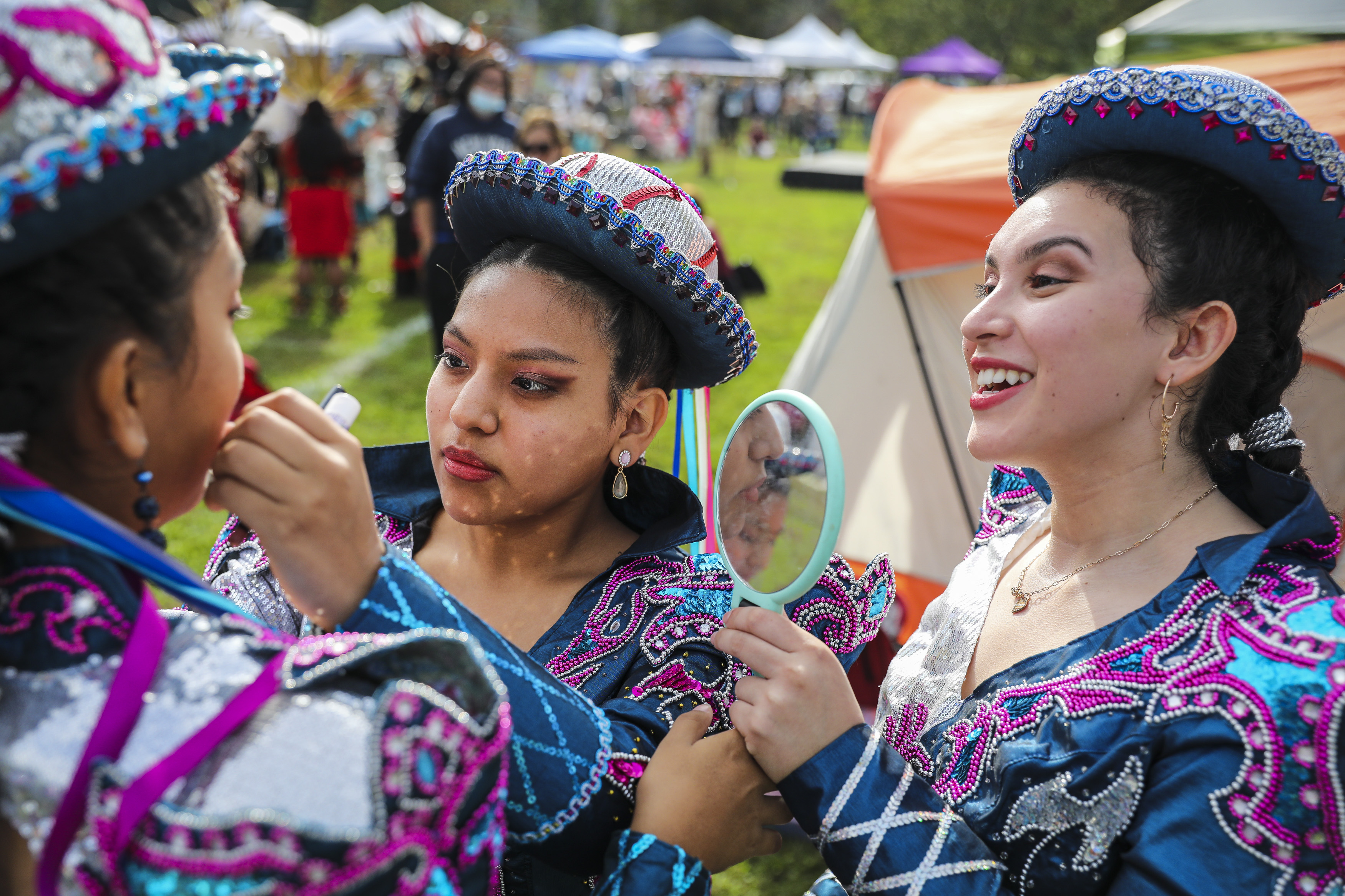 Camille Puma (from left) , Cristina Zarate and Isabella Pino, dancers from Pumawari Tusuy, touched up their makeup before performing at the Indigenous Peoples Day Ceremonial Celebration.