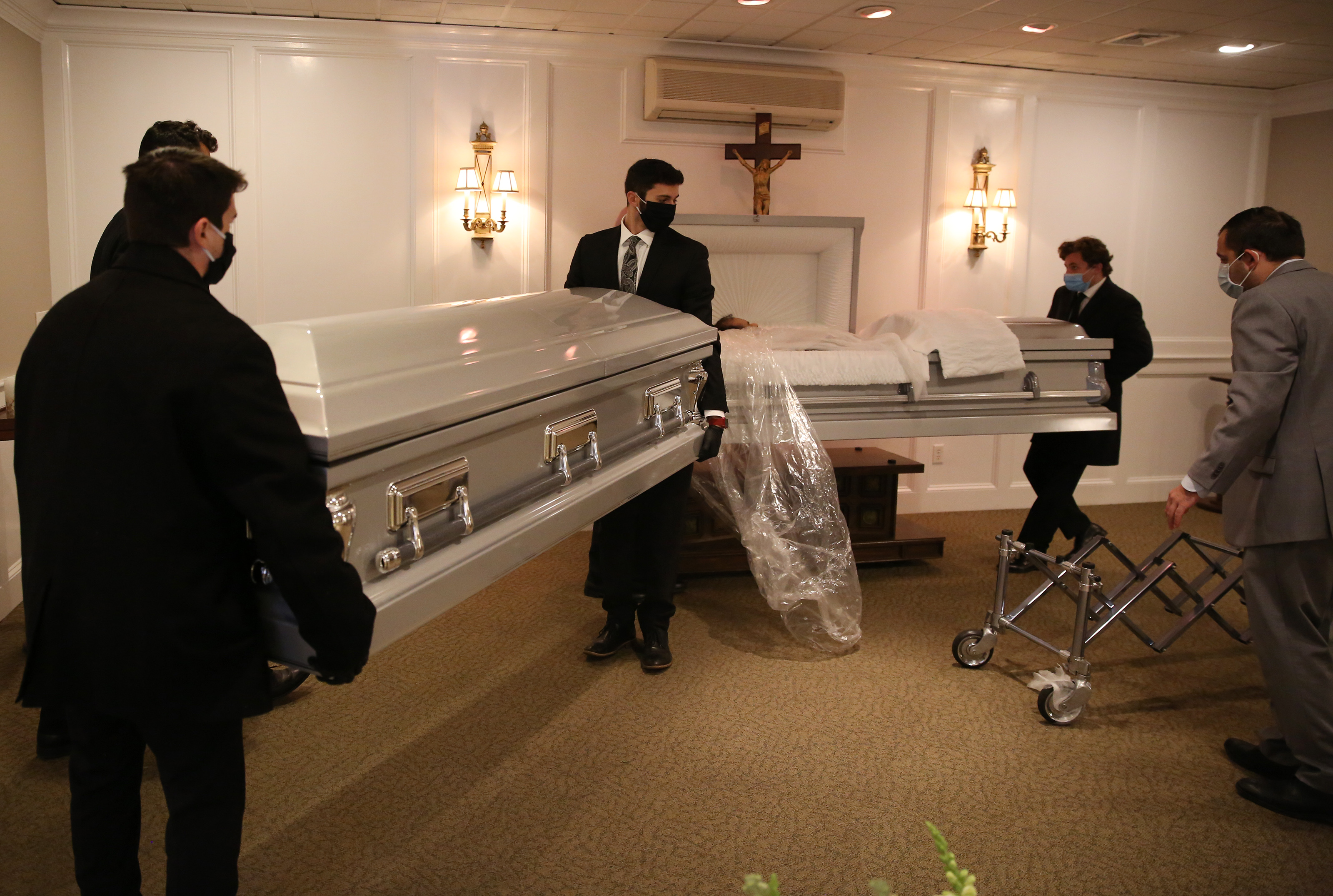 Funeral workers moved a casket out for a funeral as another was brought in to set up for a wake inside Ruggiero Family Memorial Home in East Boston.