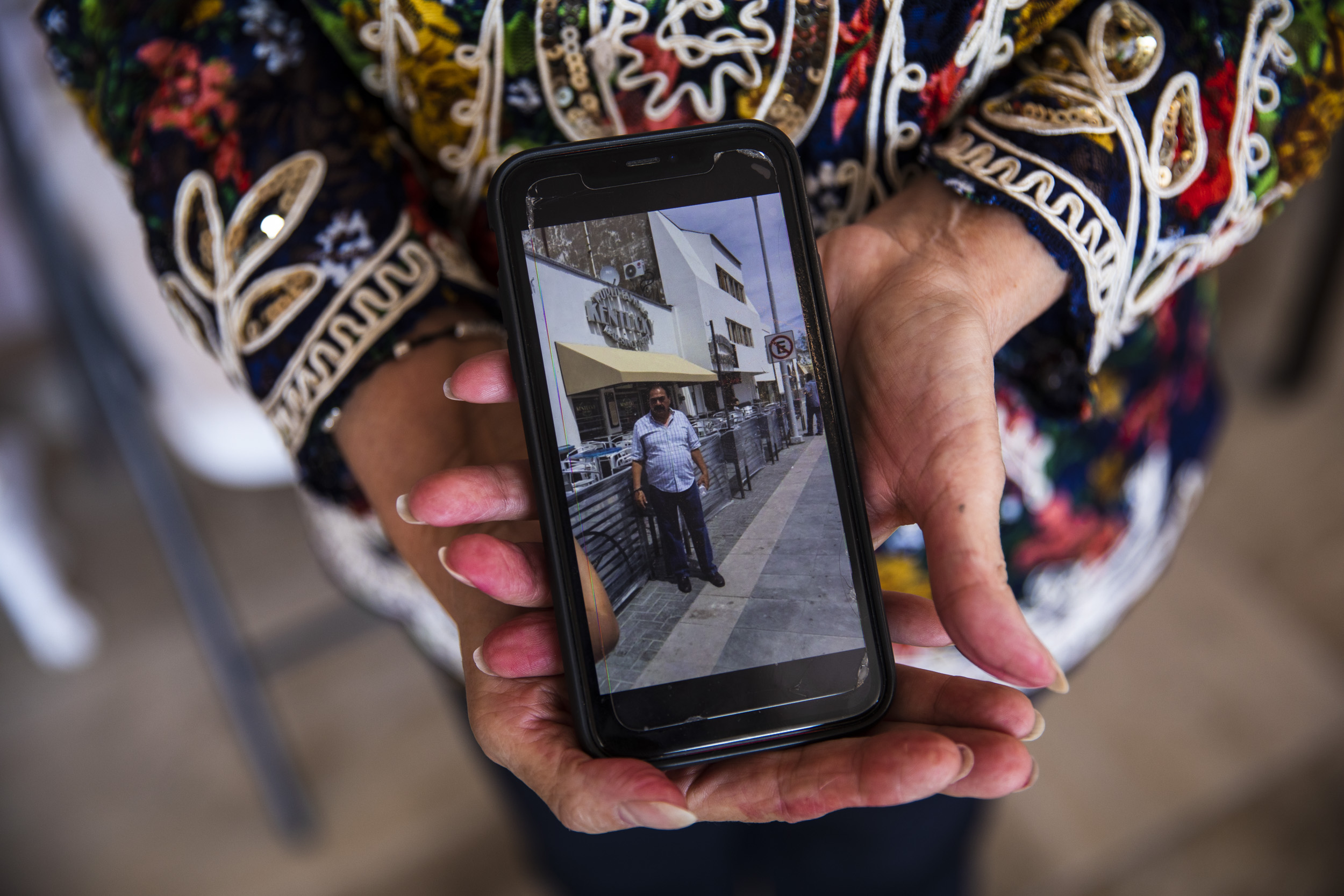 Laura Peña held a photo of her late husband, Sergio Peña Acosta, in front his bar, the Kentucky Club, in Juarez.