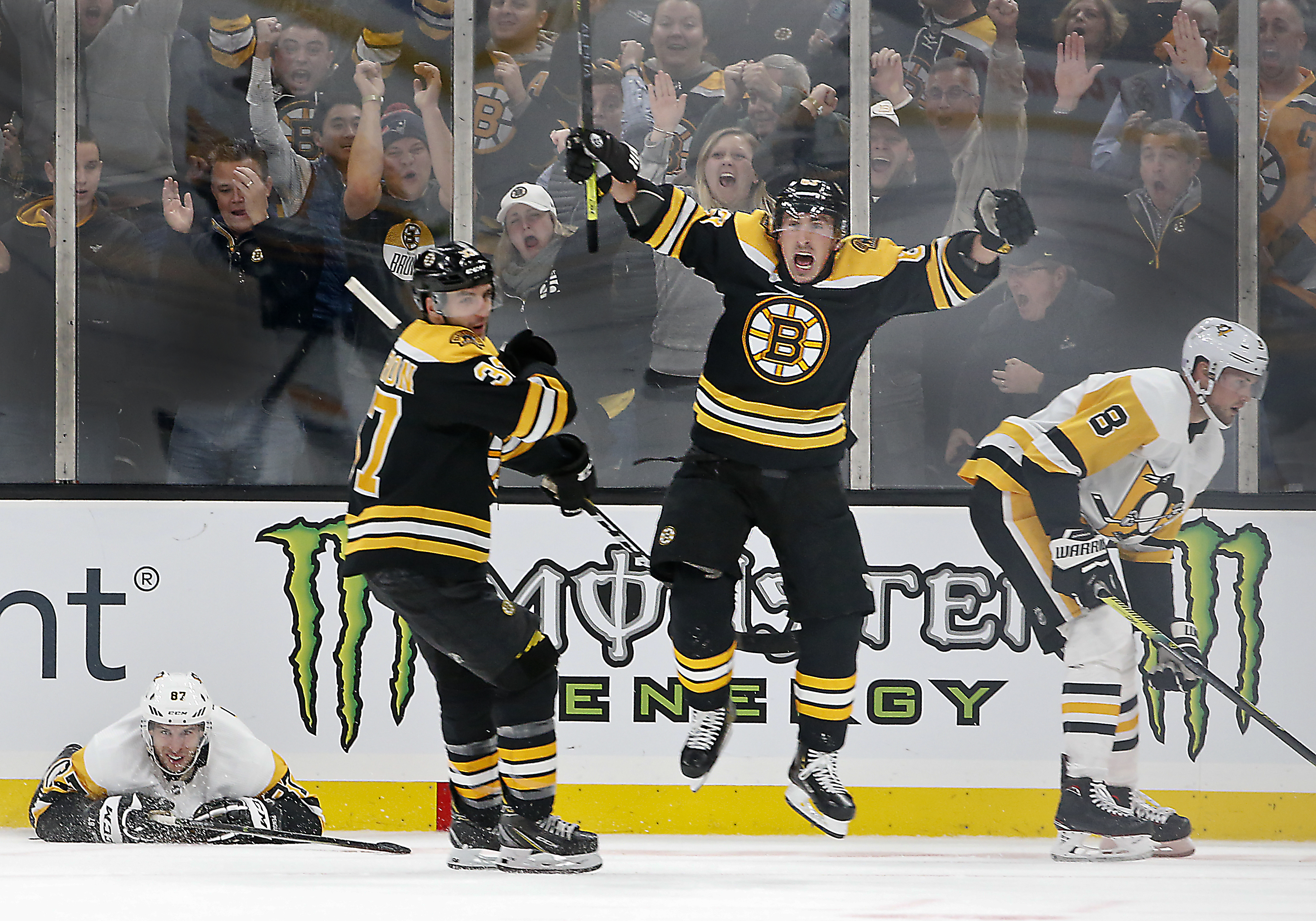 The Boston Bruins’ Brad Marchand celebrated his game-winning goal with teammate Patrice Bergeron in front of the Pittsburgh Penguins’ Sidney Crosby (left) and Brian Dumoulin (8) during the third period at TD Garden on Nov. 4. The Bruins won 6-4.