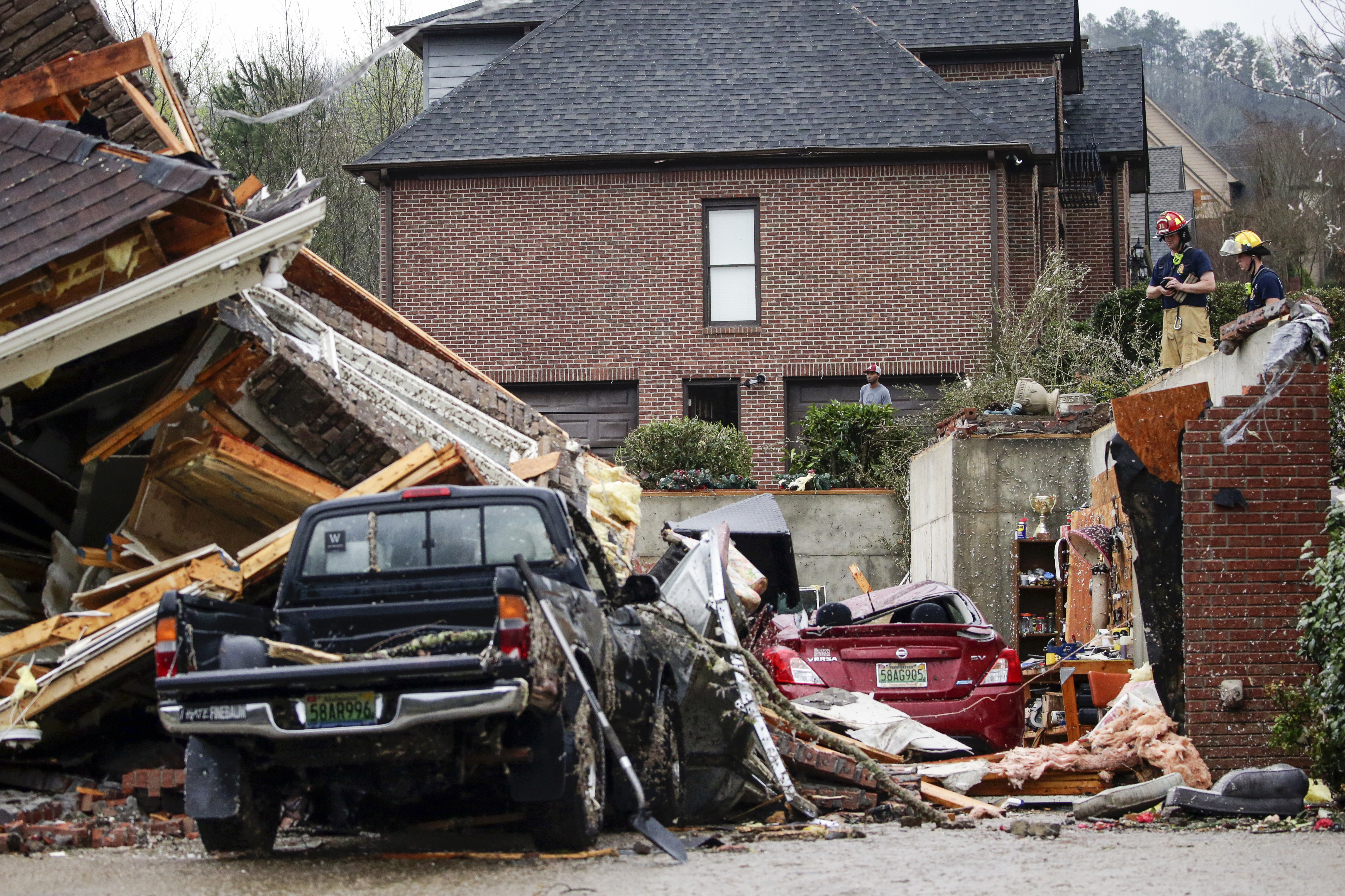A firefighters survey damage to a house where the family was trapped, but were able to get out after a tornado touches down south of Birmingham, Ala., in the Eagle Point community damaging multiple homes Thursday, March 25, 2021.