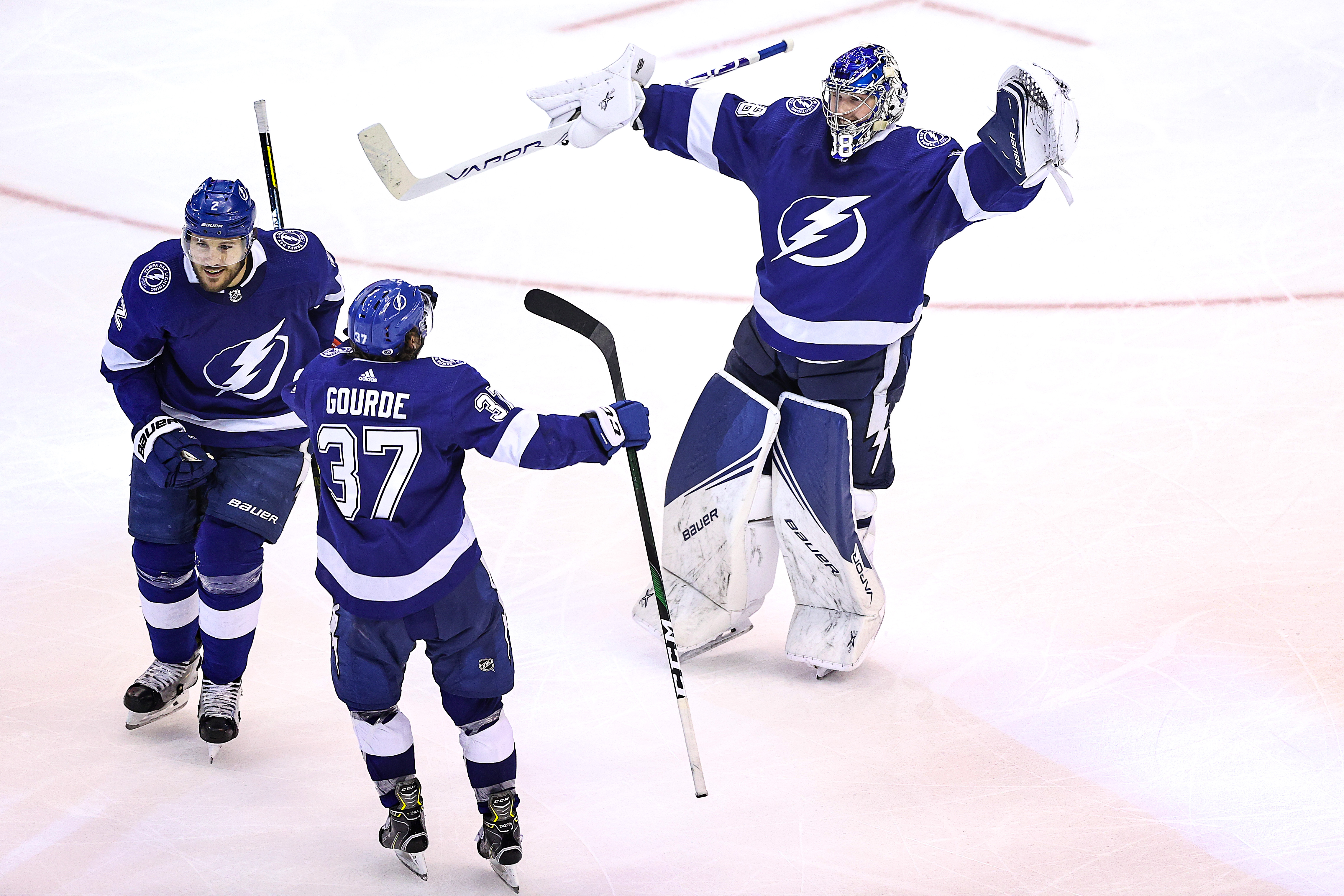 Andrei Vasilevskiy (No. 88), Luke Schenn (No. 2) and Yanni Gourde (No. 37) of the Lightning celebrate after the game winner against the Bruins Monday night.