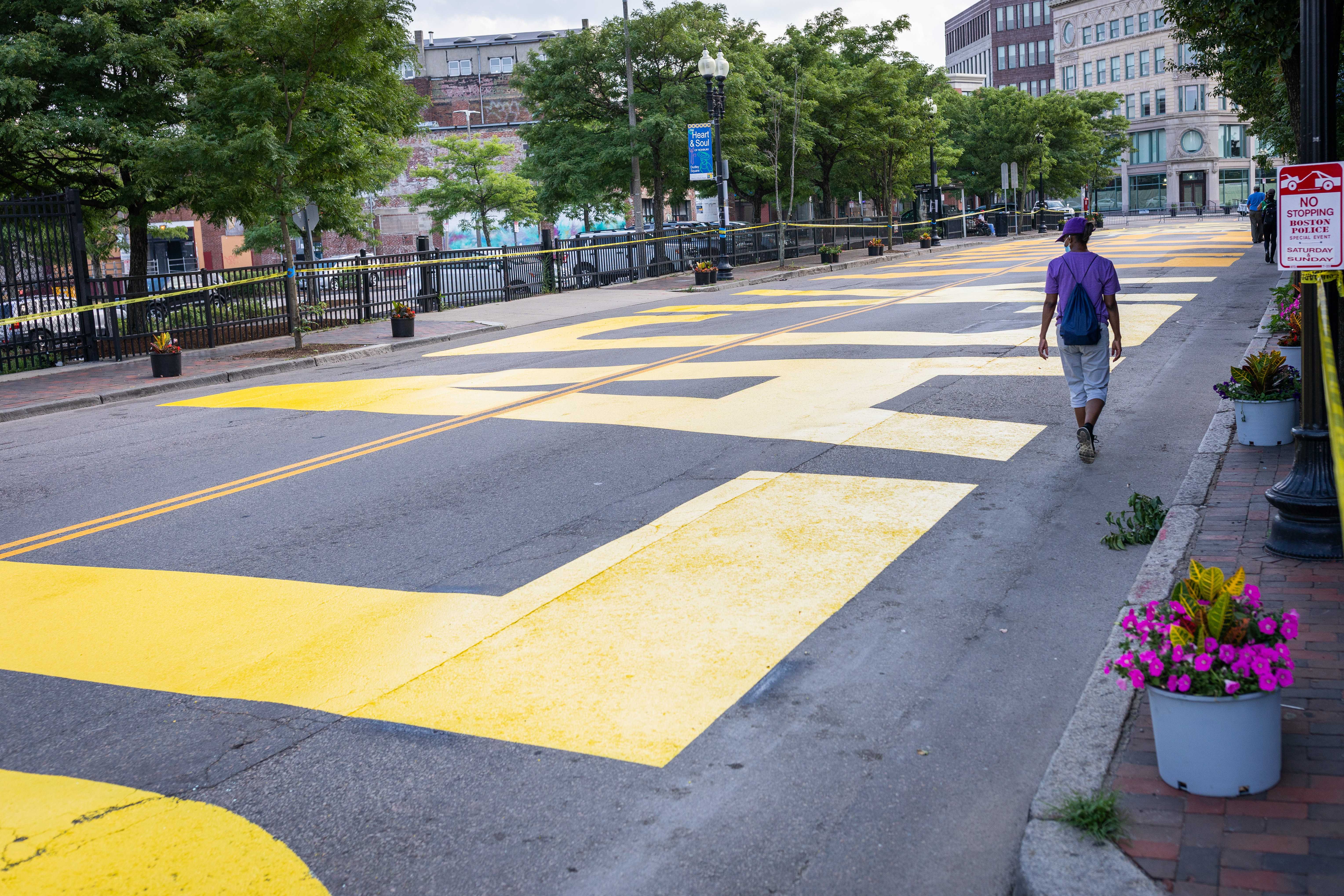 Charlene Zuill, a volunteer who helped with the murals, walked past the Black Lives Matter sign painted on Washington Street in Nubian Square in Boston on Sunday.