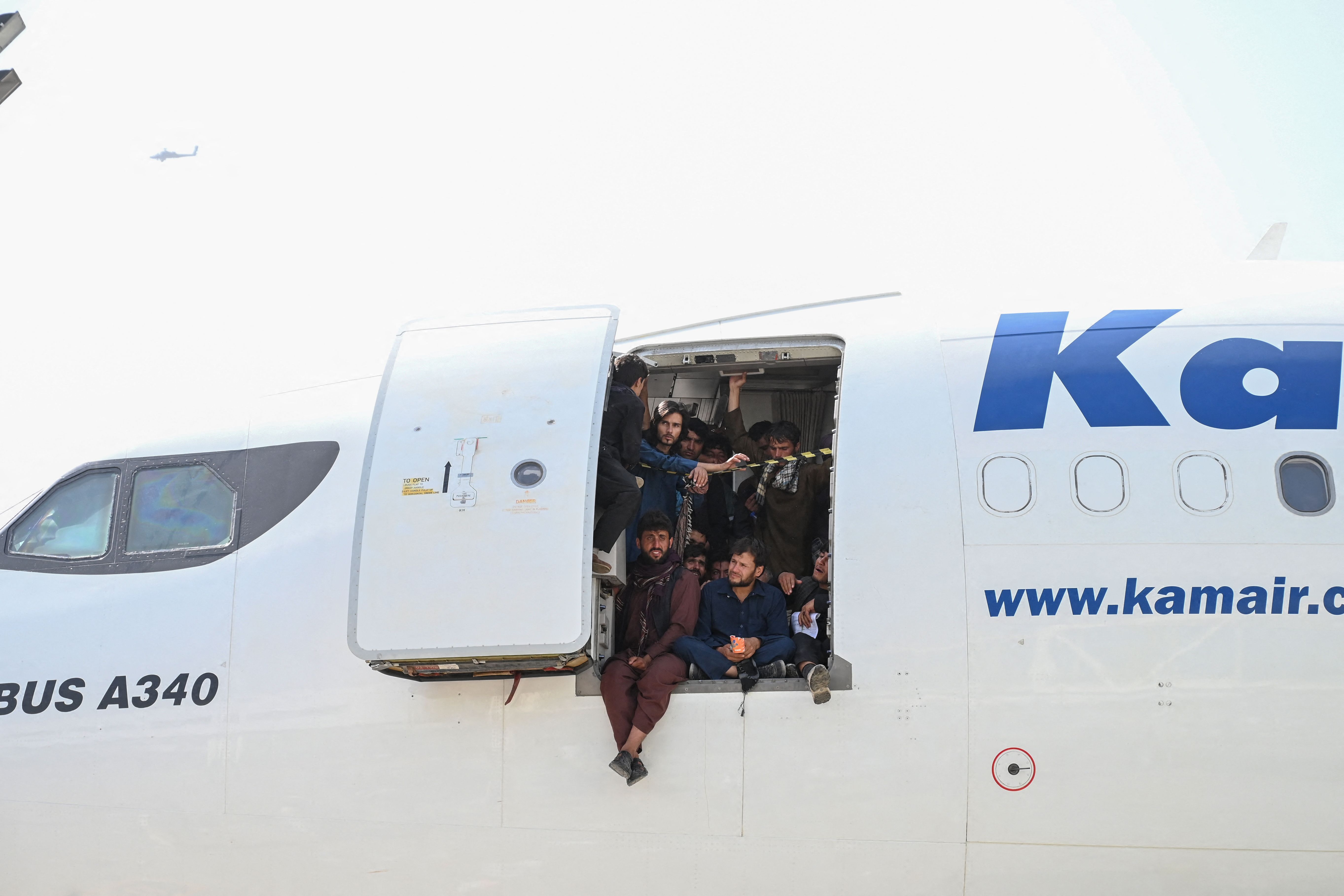 Afghan people climbed up on a plane and sat by the door as they waited at the Kabul airport.