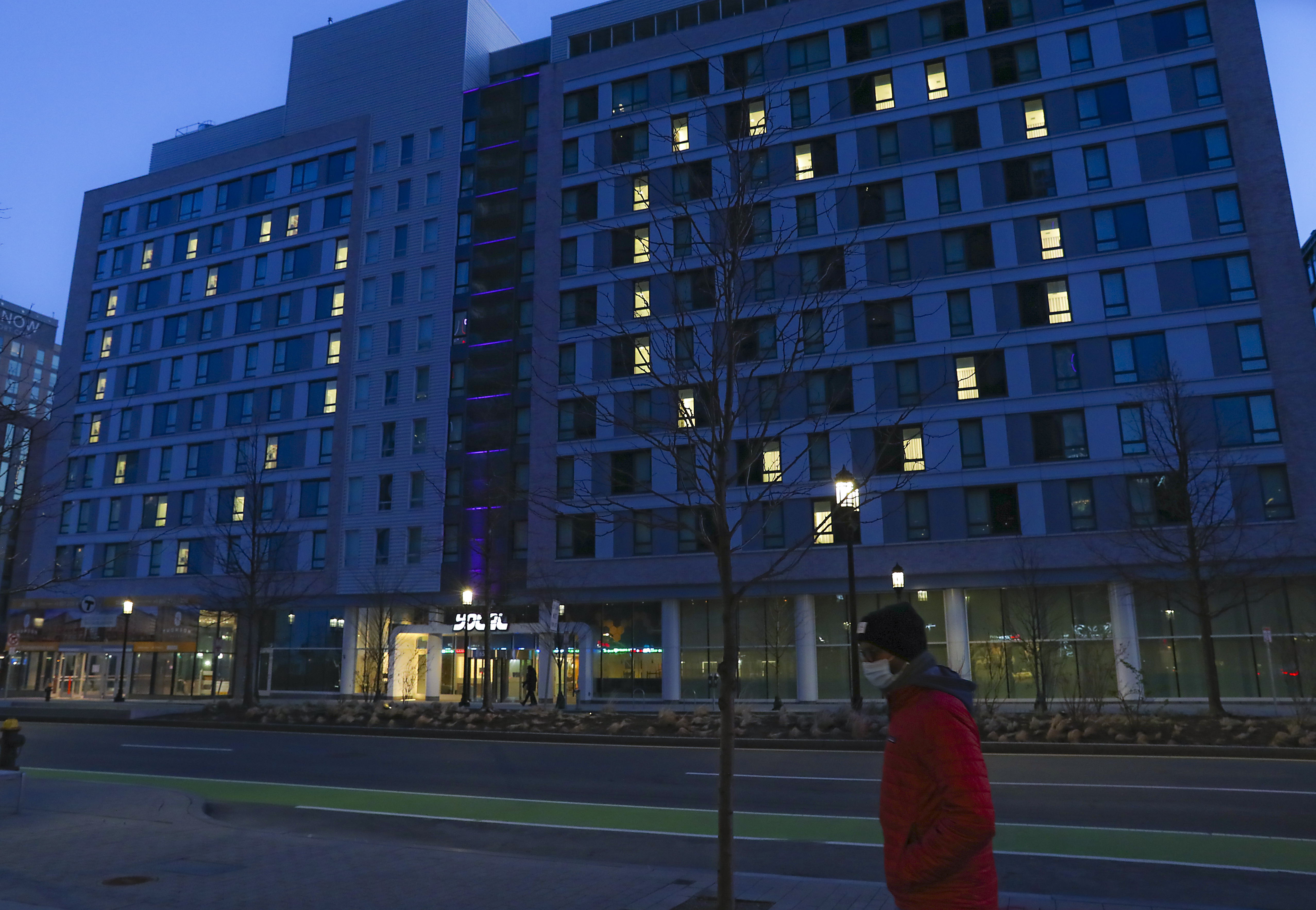 A lone pedestrian walking past Yotel Boston on Seaport Boulevard at sundown.