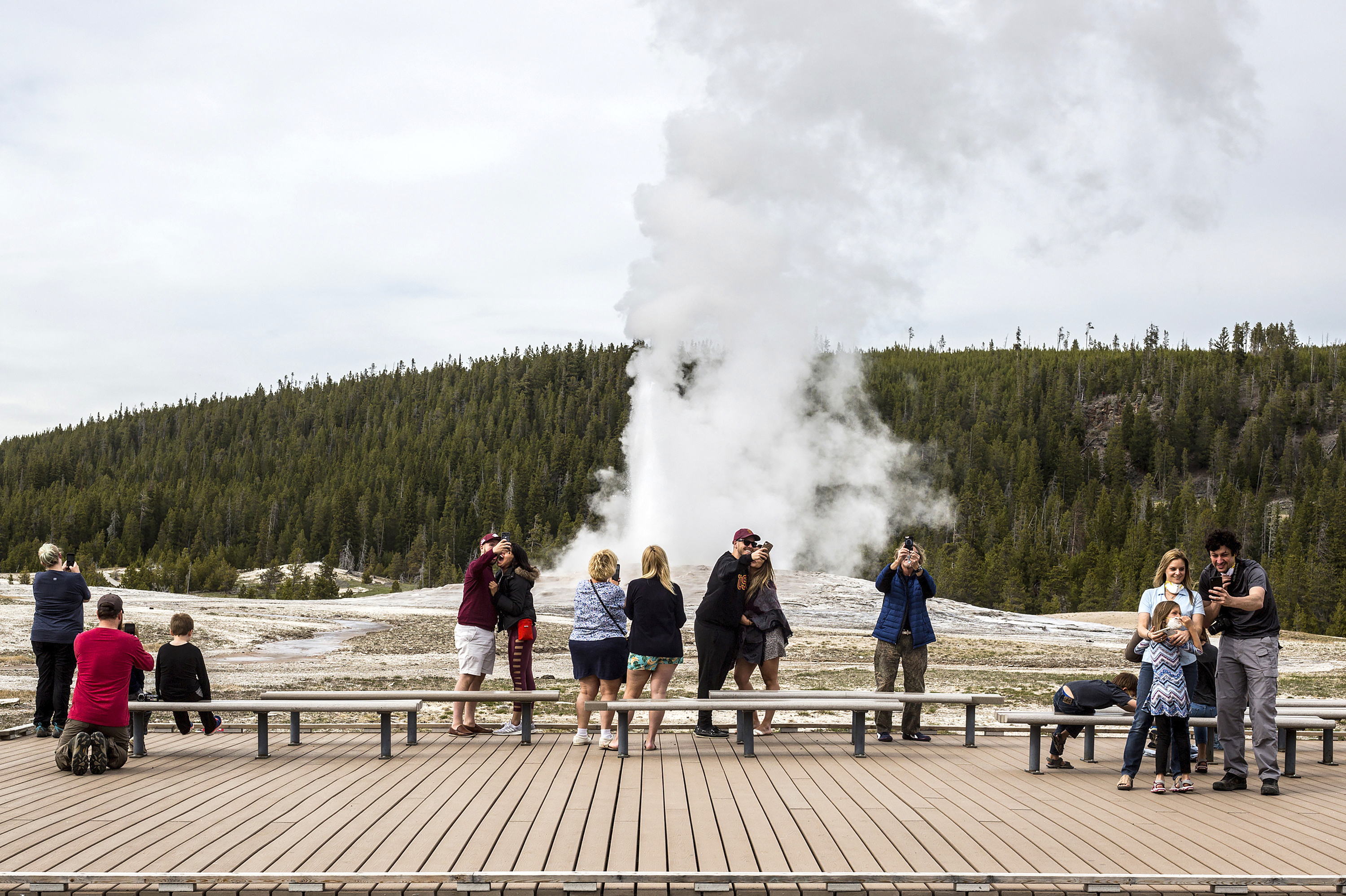 Visitors watch as Old Faithful erupts at Yellowstone National Park in Wyoming.