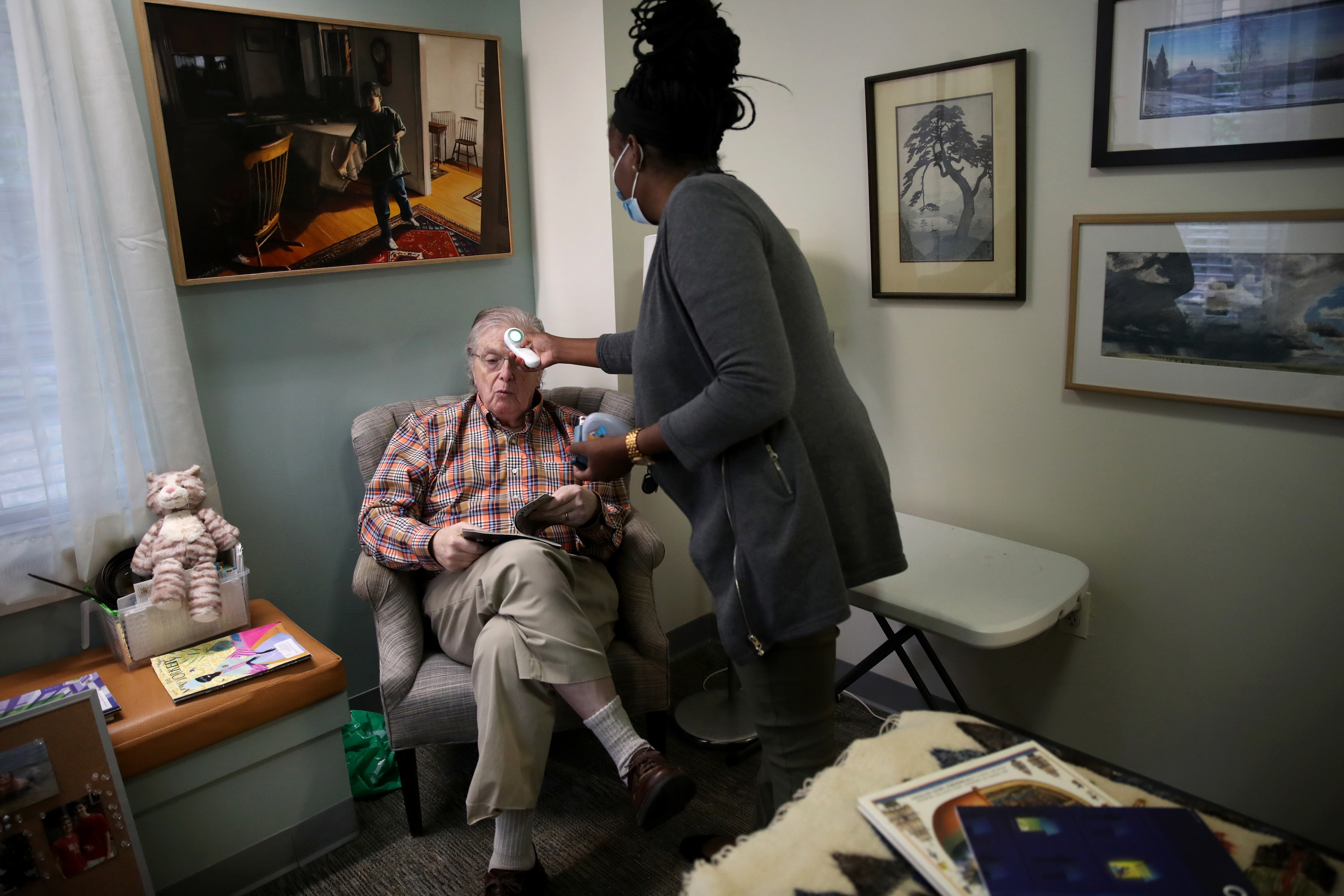 Resident George Brackett, 77, had his temperature checked by LPN Stephanie Dupervil in his room at Rogerson House in Boston.