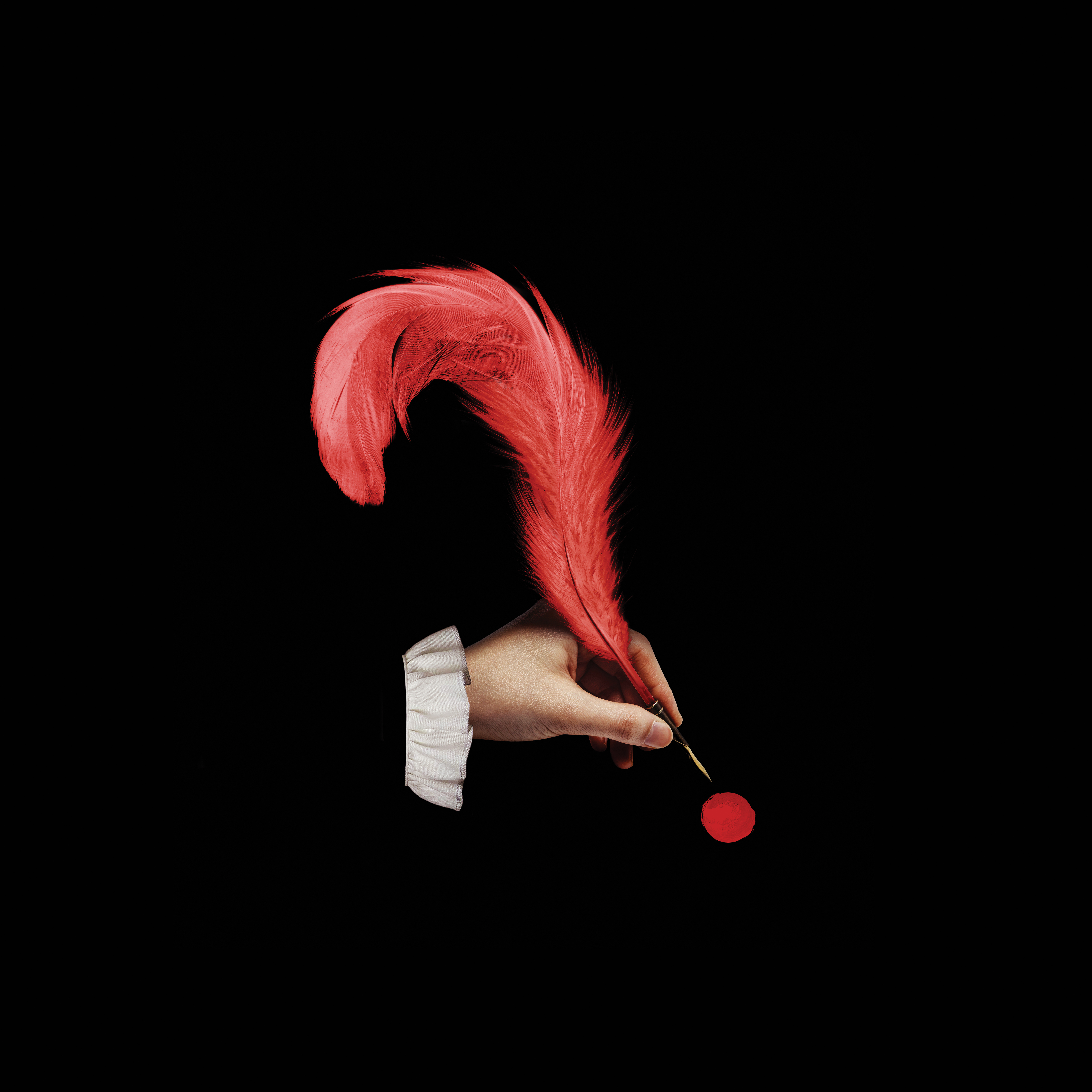 A hand writing with a feather quill shaped like a question mark.