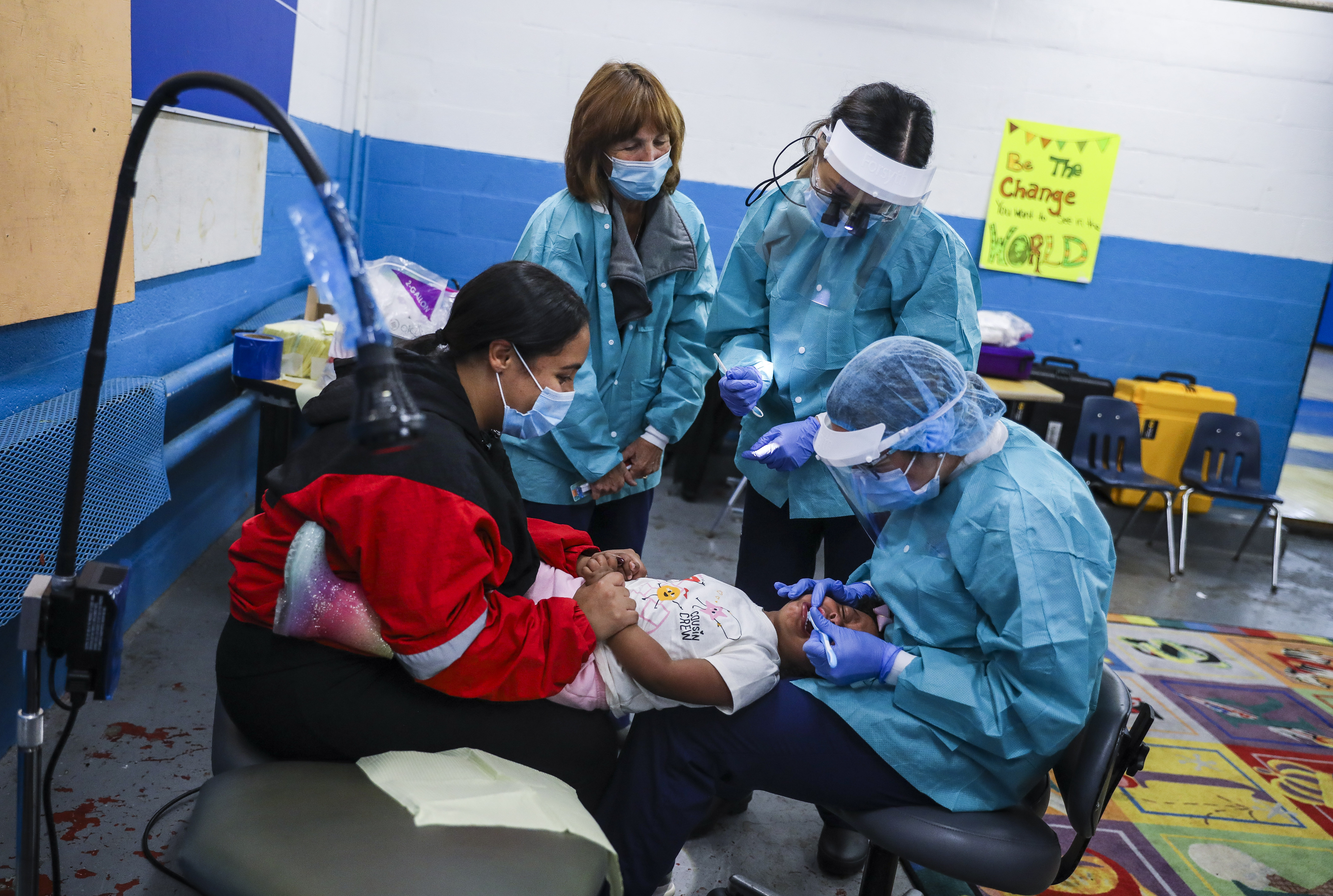 Grace Duran held her 2-year-old daughter, Emma Alvarez, while ForsythKids dental hygienist Roquel Norris took a look at her teeth with the help of dental assistant Linda Joyce (left) and dentist Helen Nguyen.
