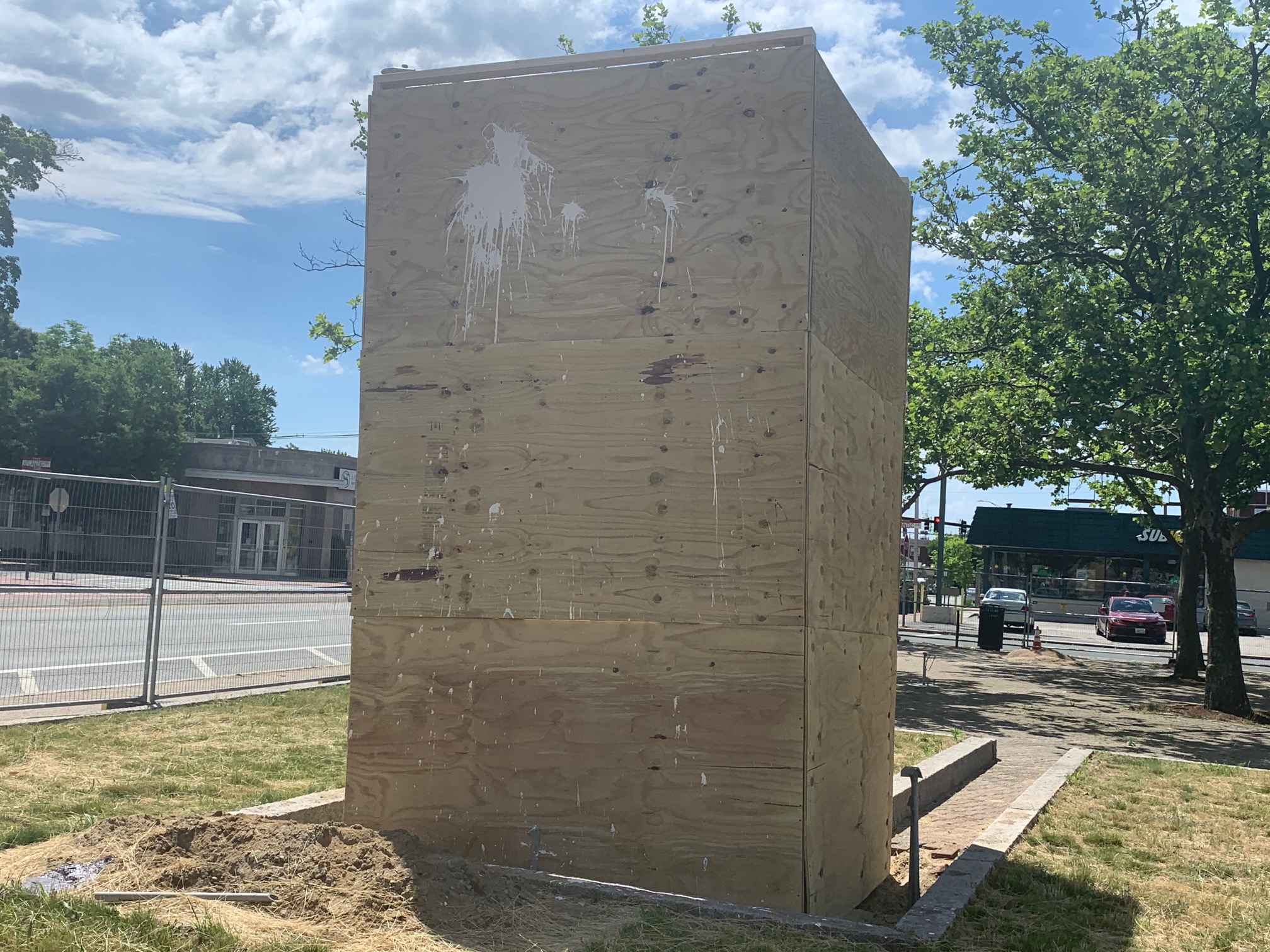 The boarded up statue of Christopher Columbus in Providence, with paint splattered on wood.