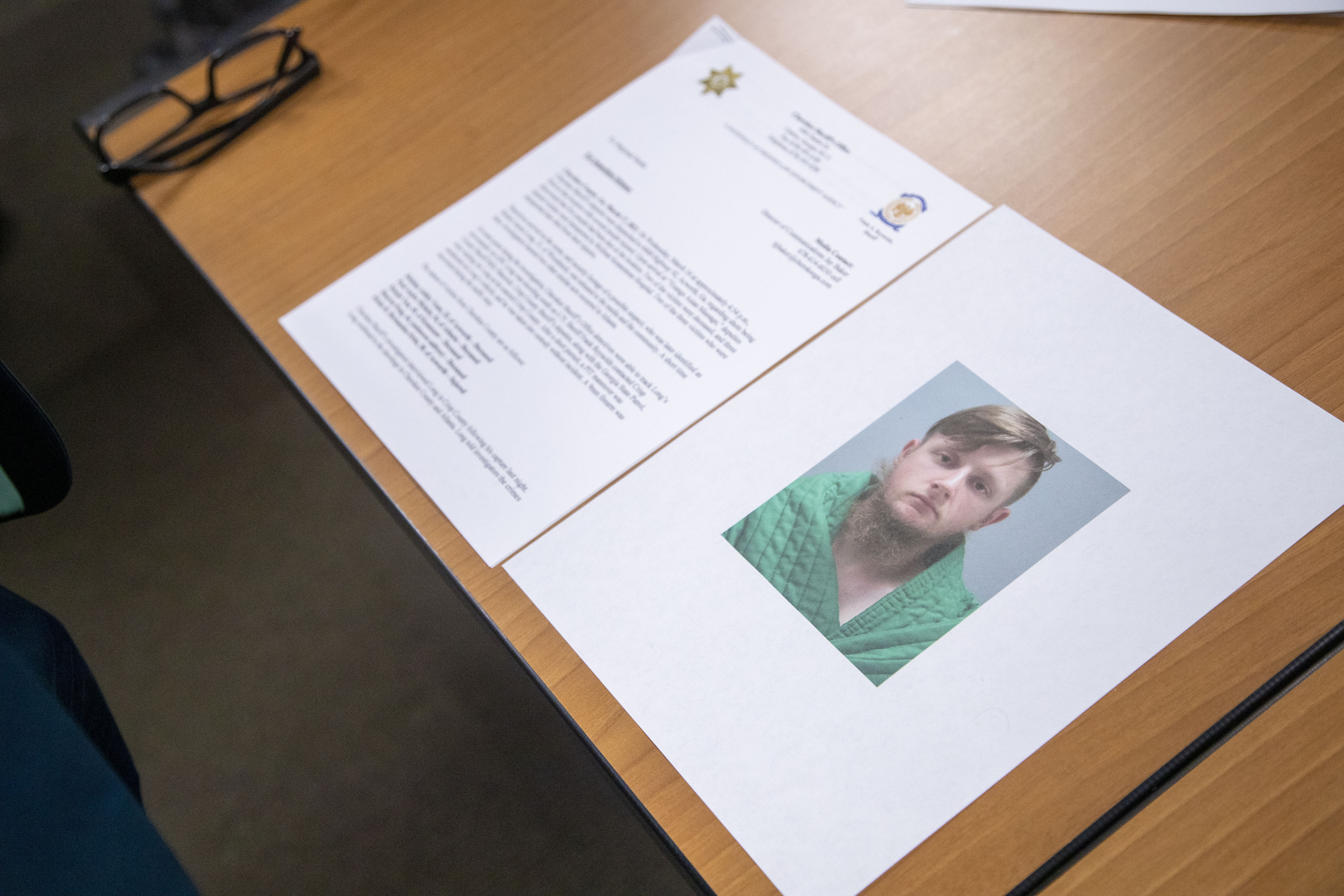 An image of Robert Aaron Long is displayed near a press release provided by the Cherokee County Sheriff's Office during a press conference at the Atlanta Police Department headquarters in Atlanta on Wednesday.