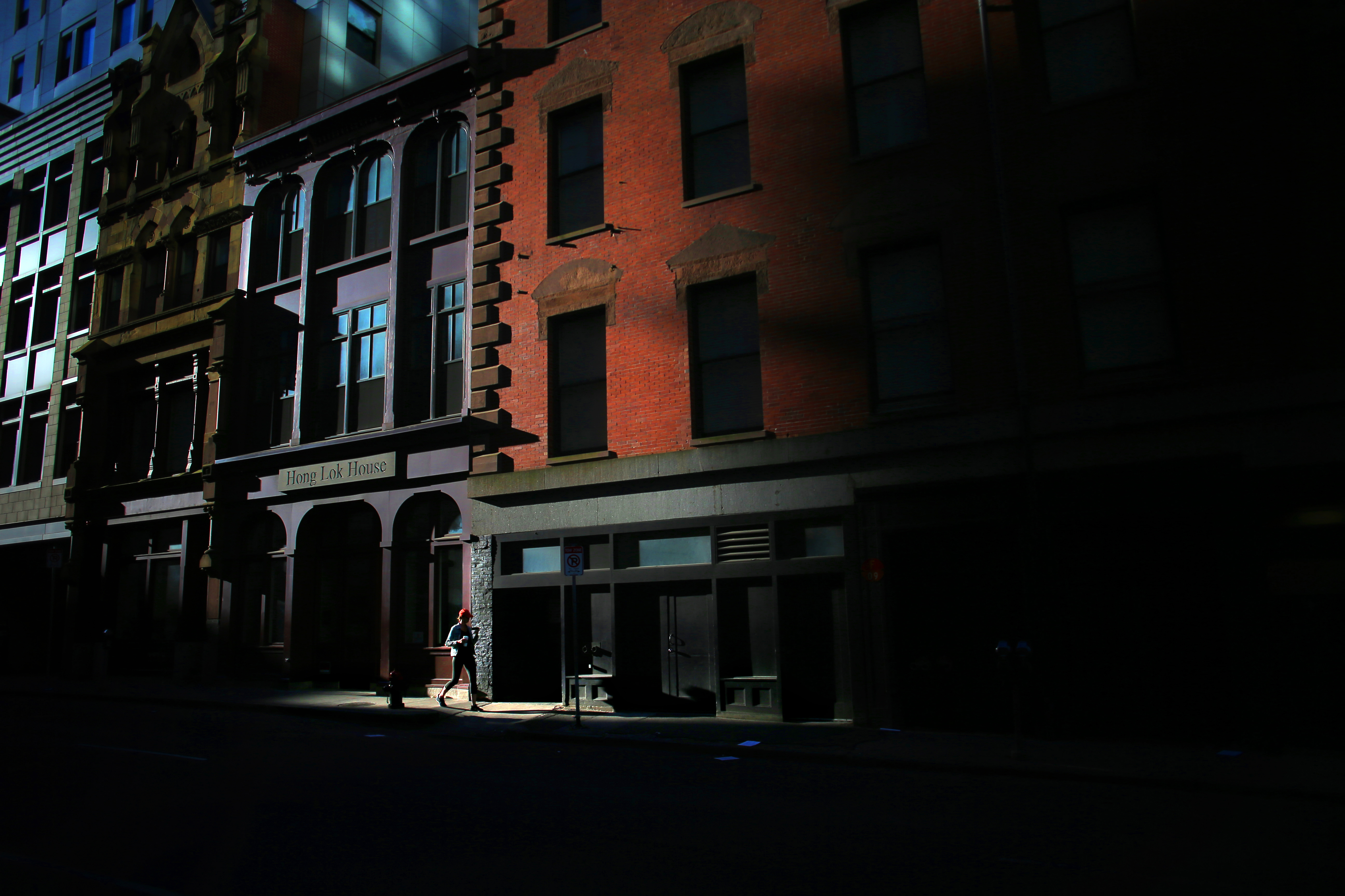 A shaft of early morning light illuminated a pedestrian passing the Greater Boston Chinese Golden Age Center and Hong Lok House on Essex Street in Chinatown.