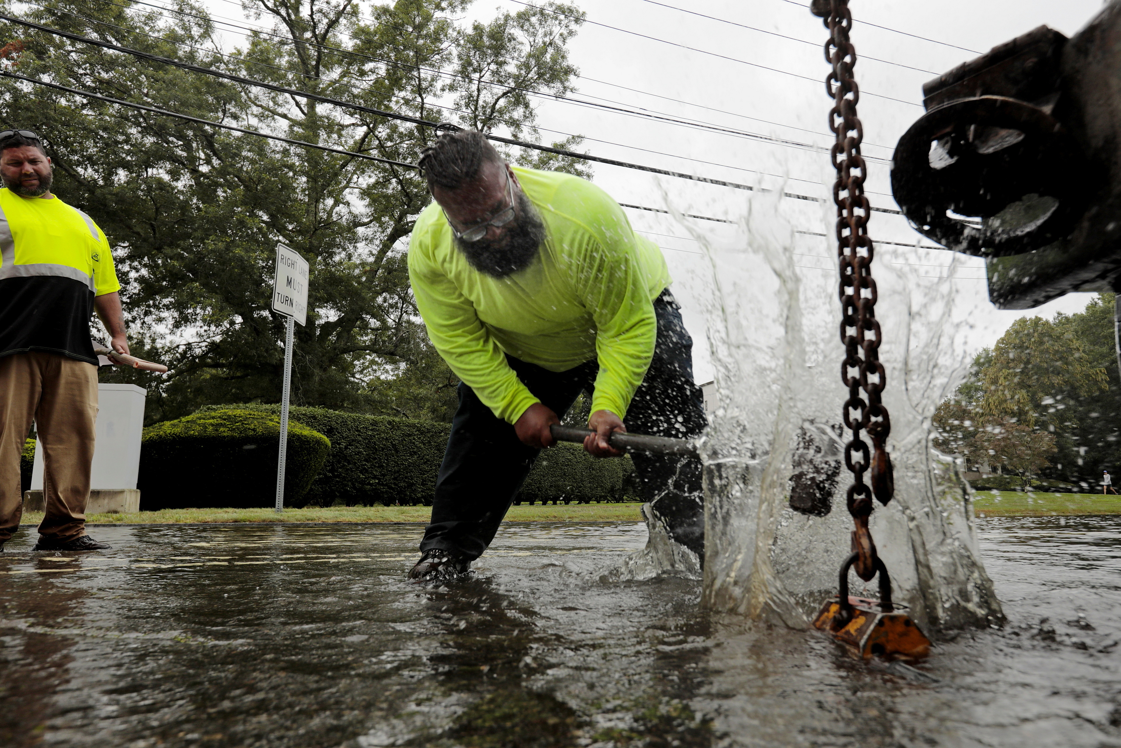 Felix Bruno-Galindez of New Bedford DPI, uses a sledgehammer in an effort to dislodge a manhole cover on Brownell Avenue in New Bedford, Mass., flooded due to the remnants of Hurricane Ida Thursday.
