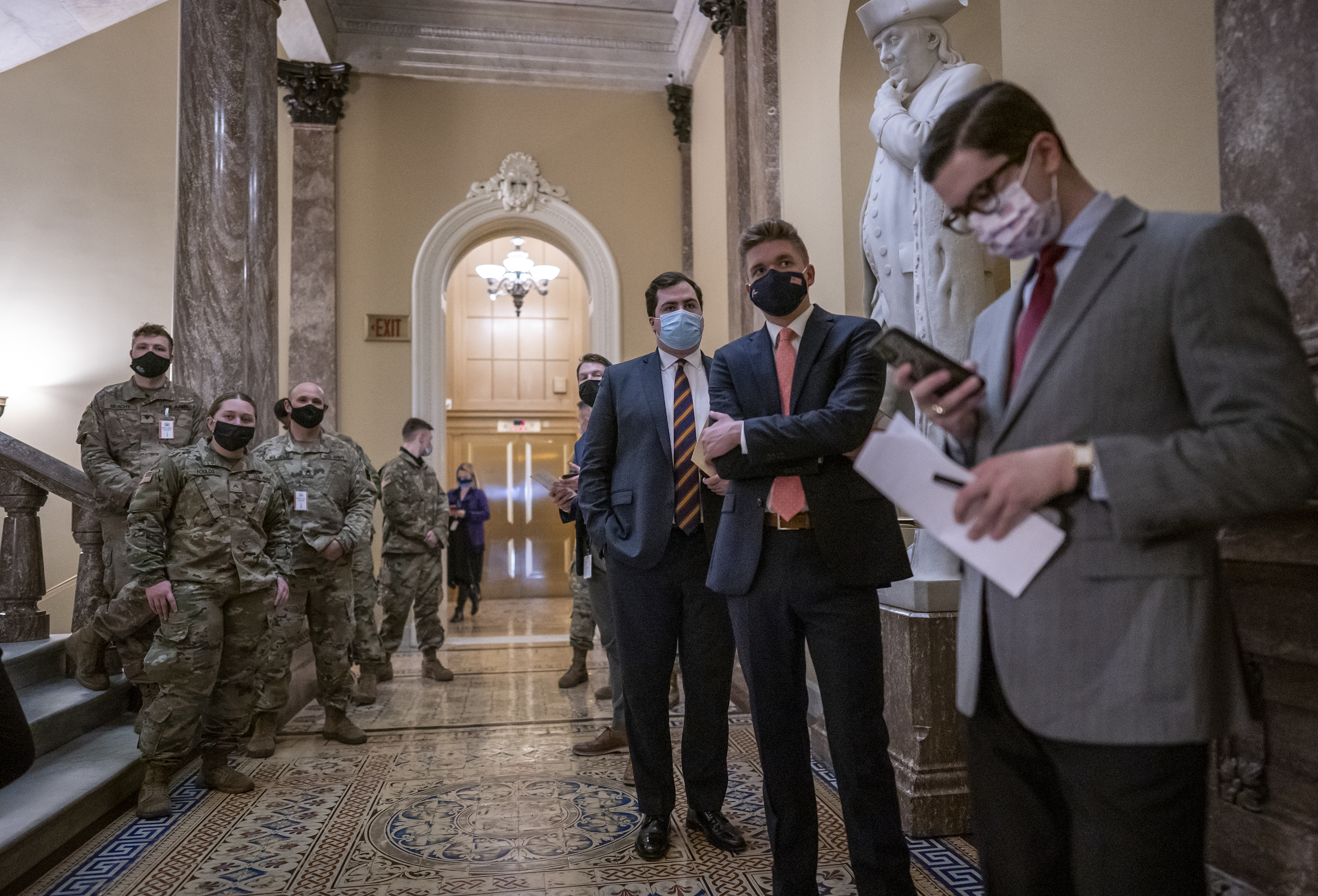 Senate staff, reporters, and visiting National Guard troops, left, waited in a corridor just outside the chamber during a vote on how to proceed on the impeachment against former president Donald Trump, at the Capitol in Washington on Tuesday.
