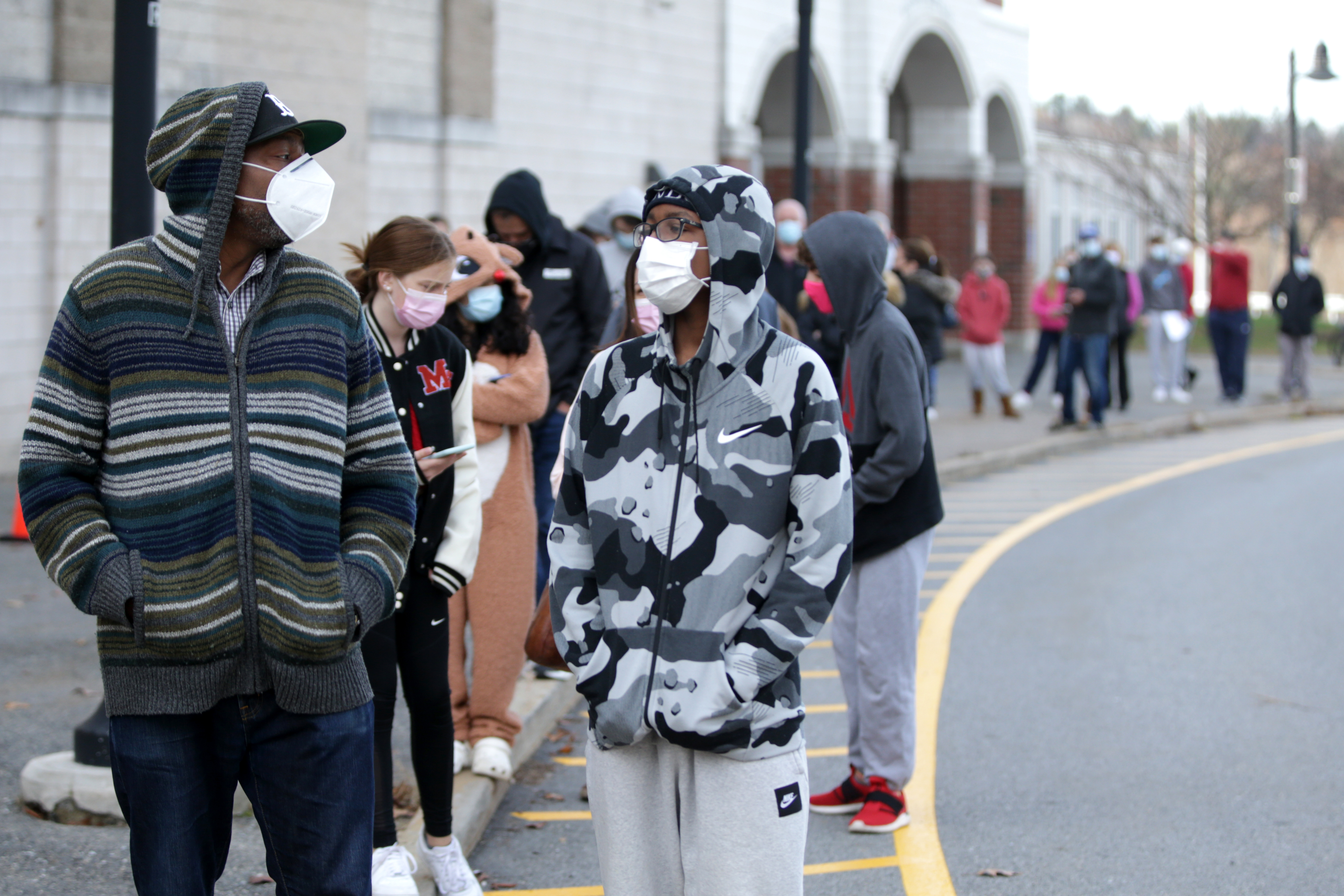 Milton High School offered COVID testing for students and families after several infections were reported at the school. Karel Lindor, left, waited in line with his son, Khamani Lindor, 16, for testing. (Jonathan Wiggs/Globe Staff)