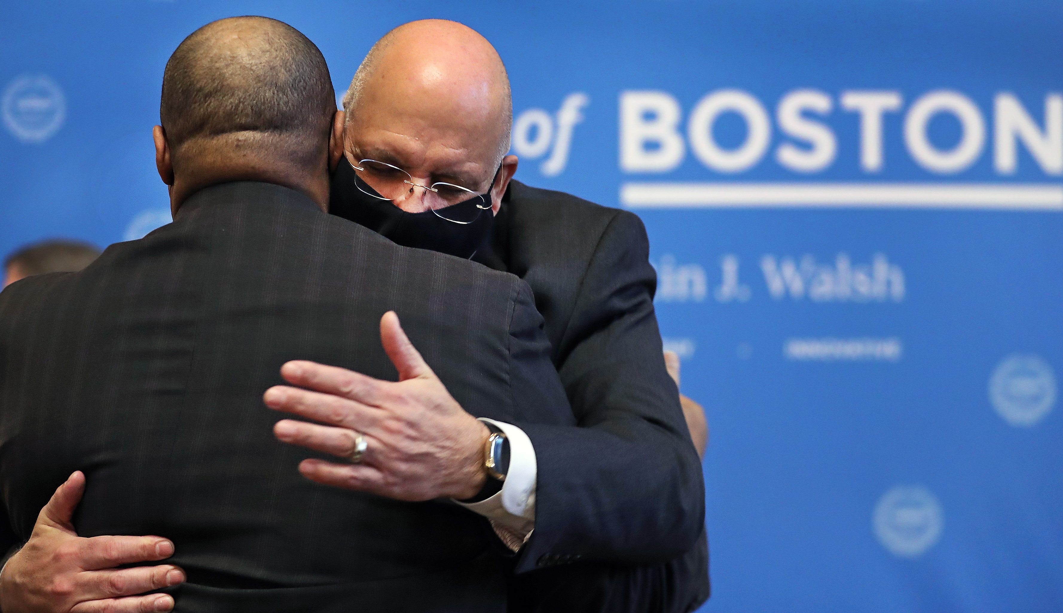 Outgoing commissioner William Gross (front) gave Dennis White a hug after the ceremony.