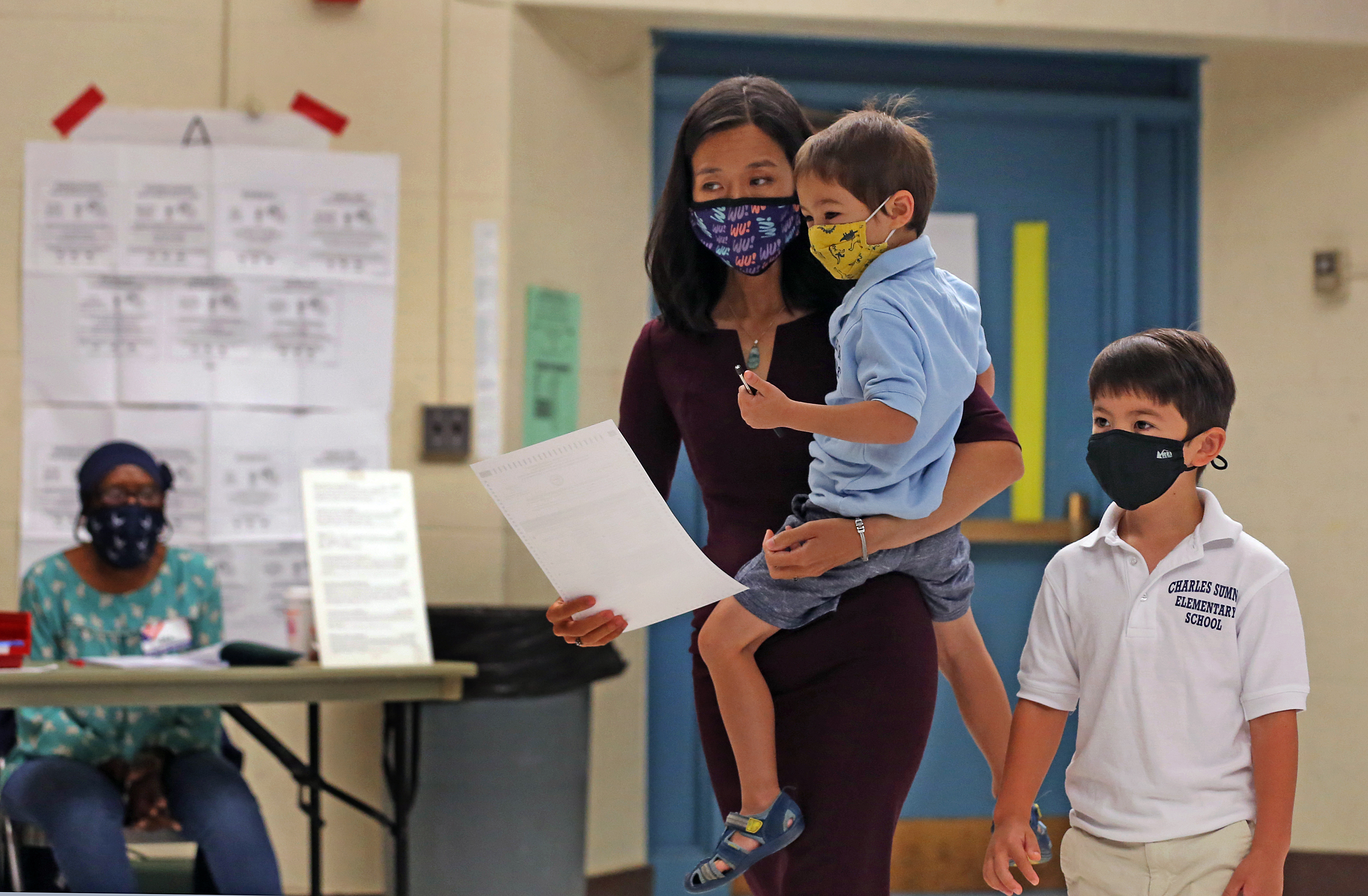 Michelle Wu walks toward the ballot box with her son Cass 4yrs old and Blaise 6yrs old on the right.