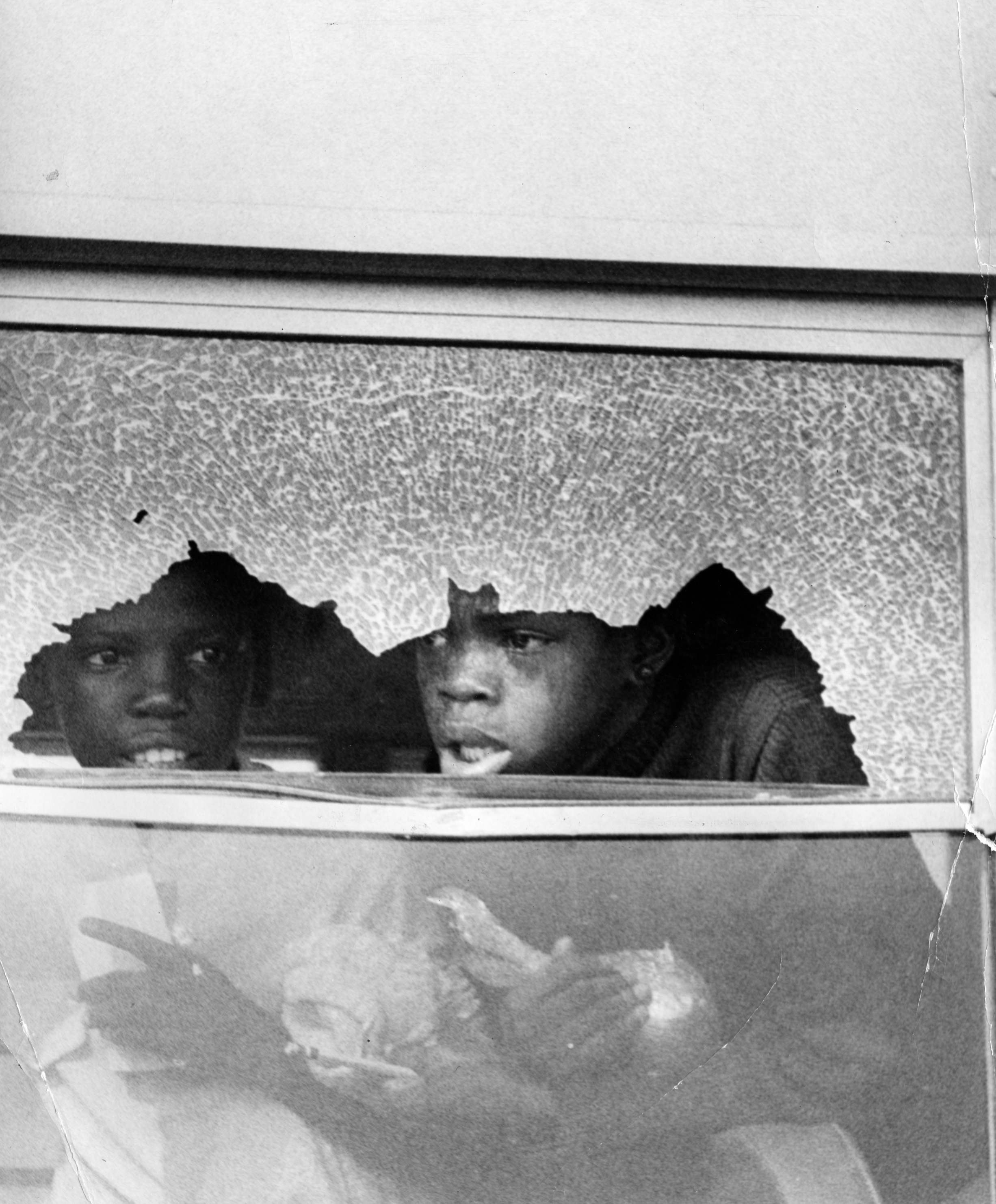 Boston students look out of a broken school bus window on Sept. 12. 1974.